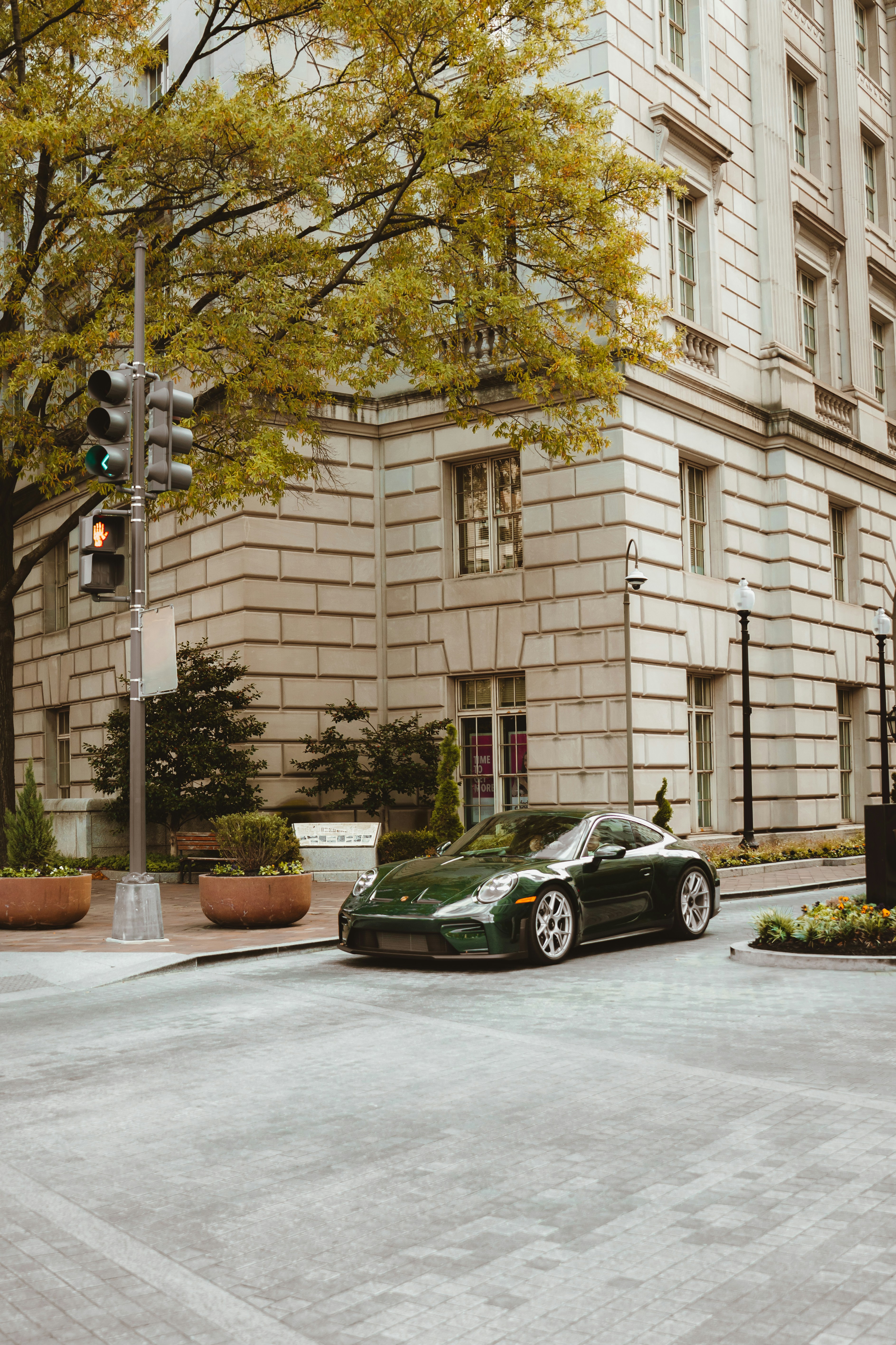 Green luxury car parked on city street corner.