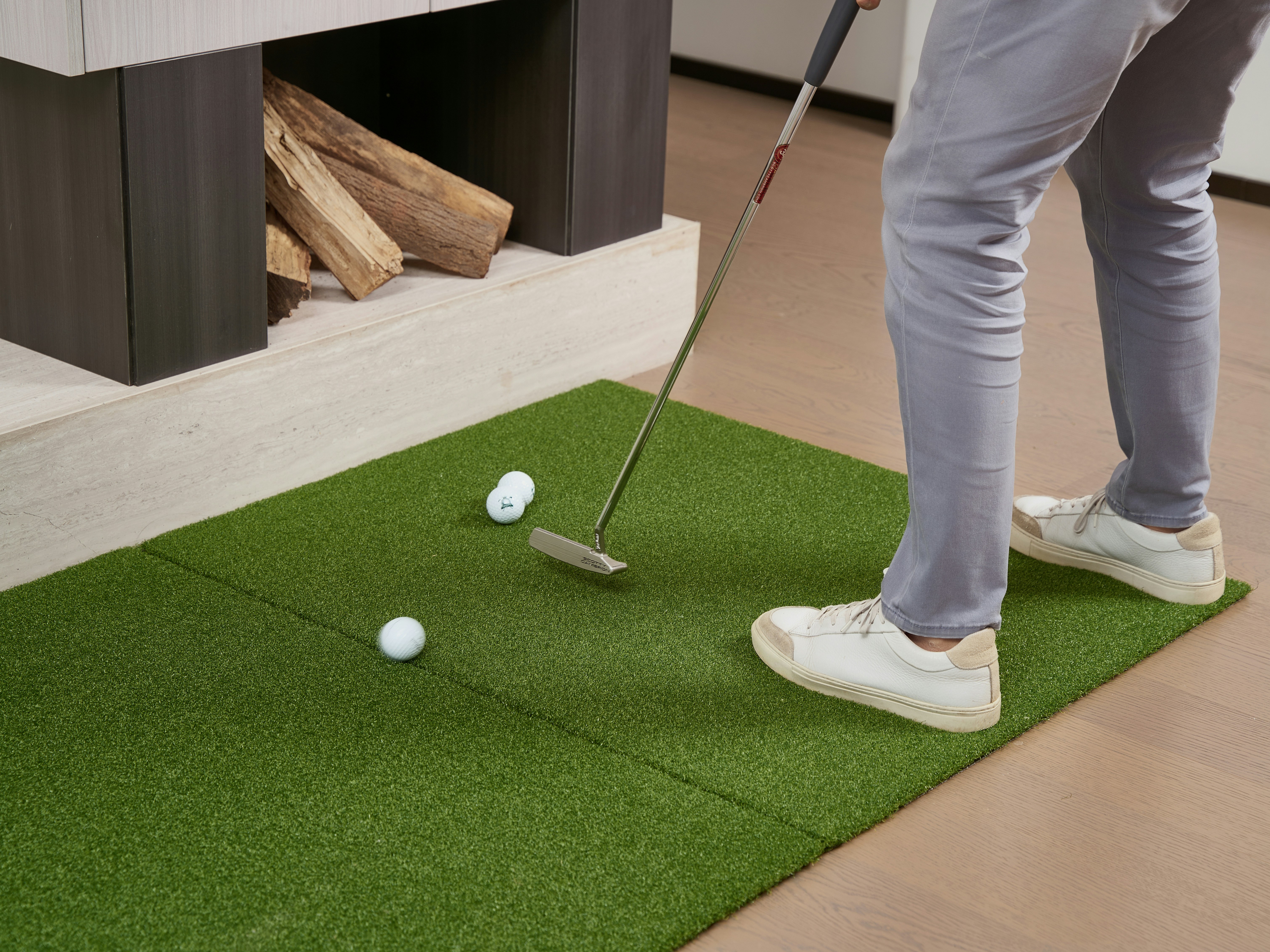 Person practicing golf putt on indoor putting green.