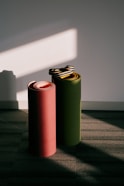 Two rolled yoga mats stand against a wall.