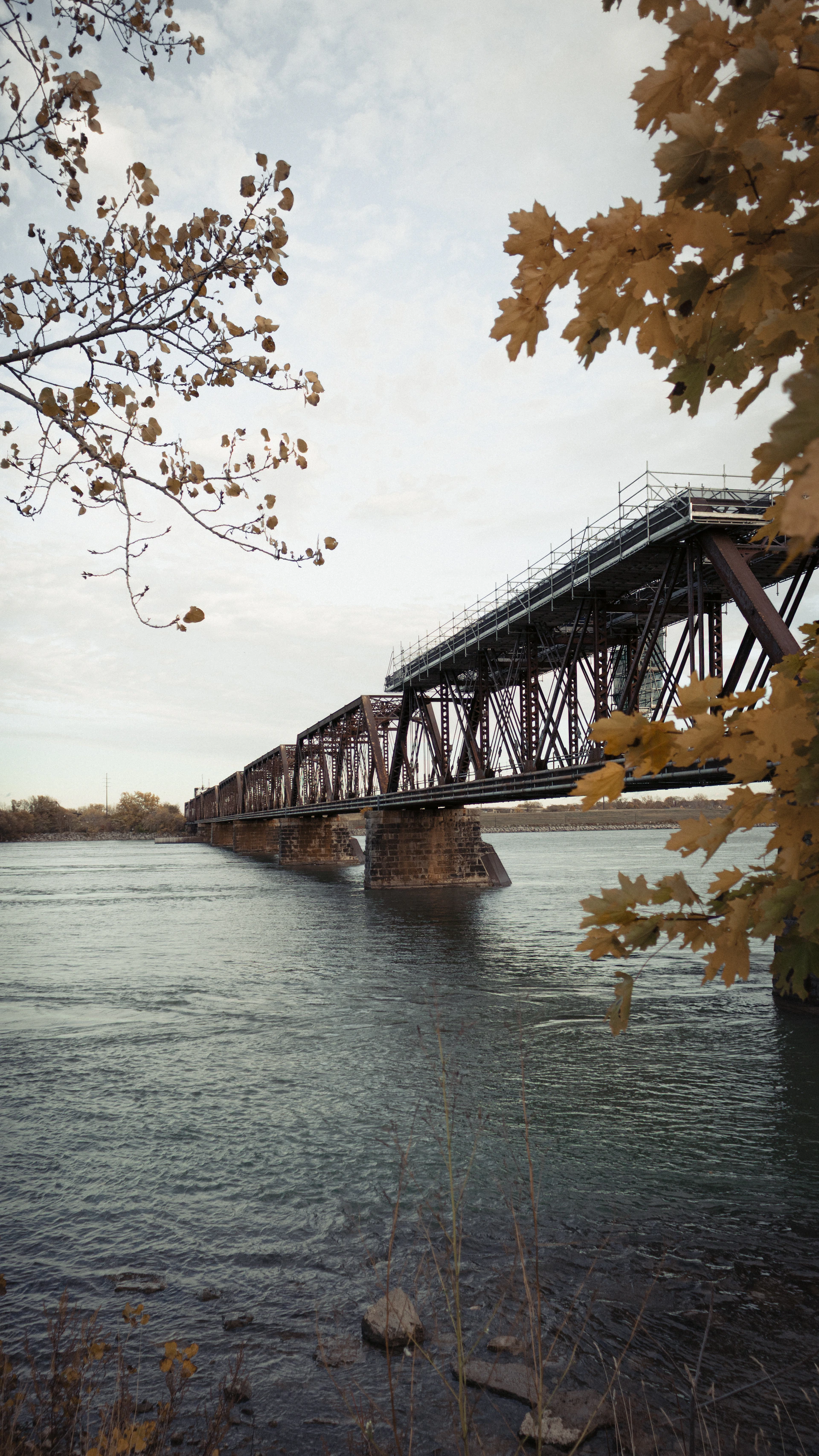 A long railway bridge crosses a wide river.