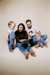 Family reading a book together on the floor.