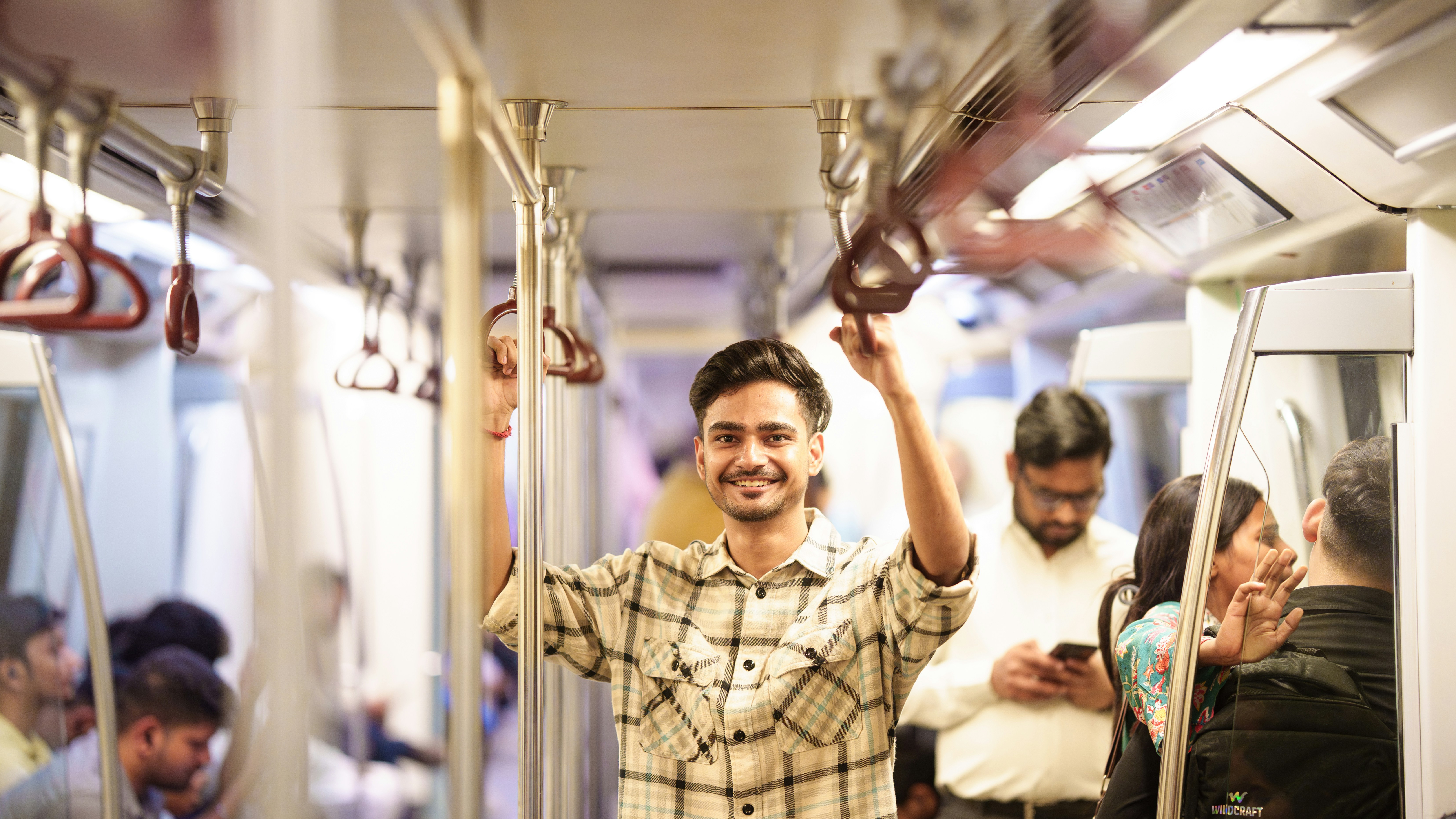 Man smiling while holding onto subway handrail
