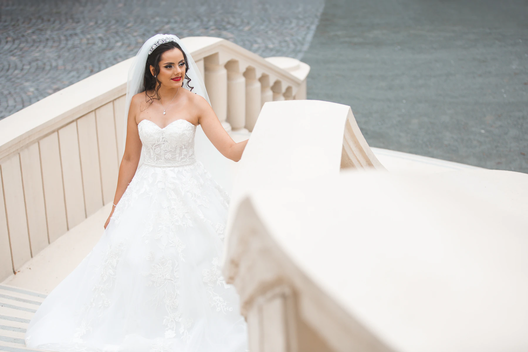Bride in a strapless lace gown on a stone staircase