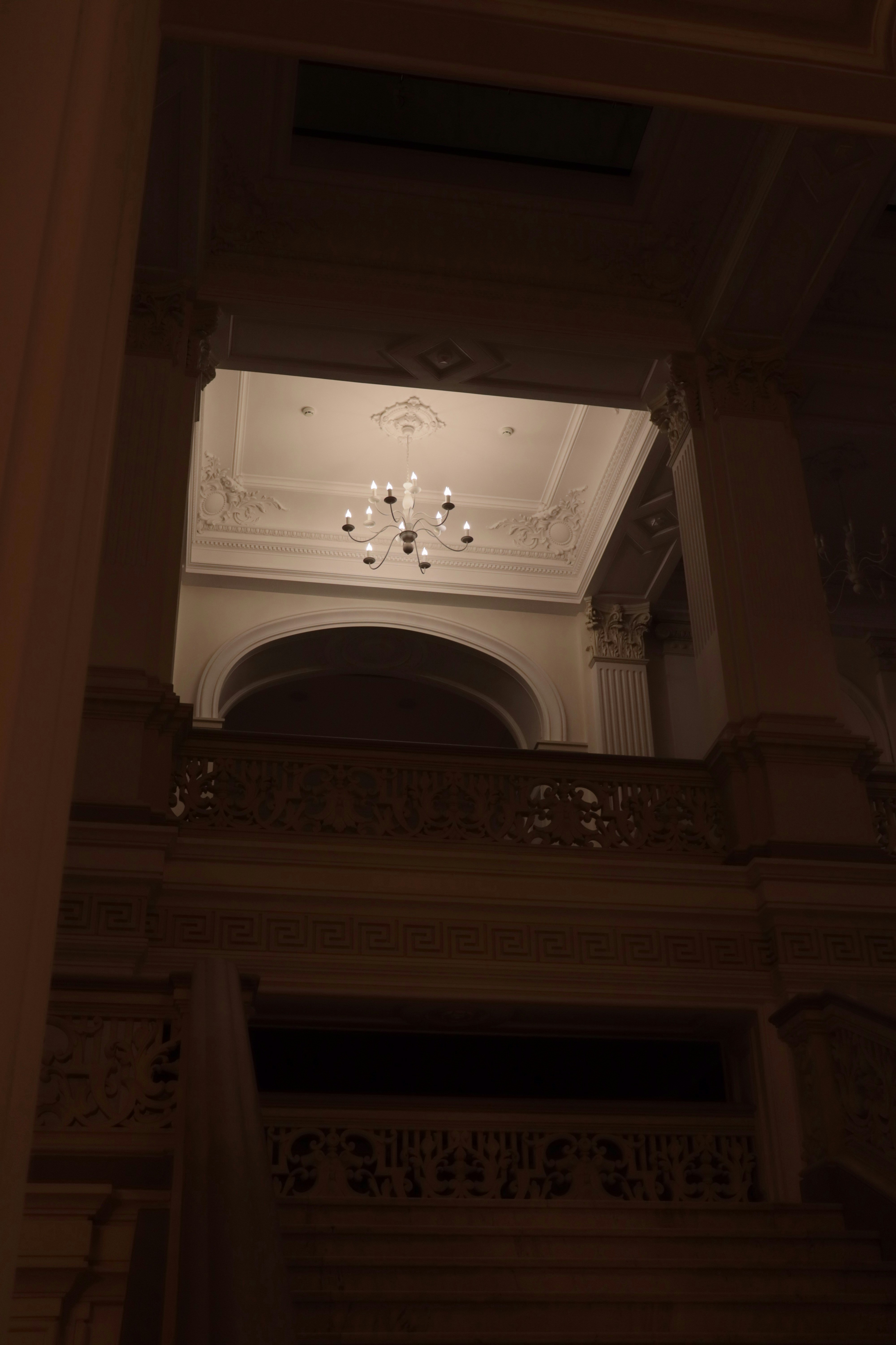 Ornate chandelier hangs in a grand, dimly lit hall.