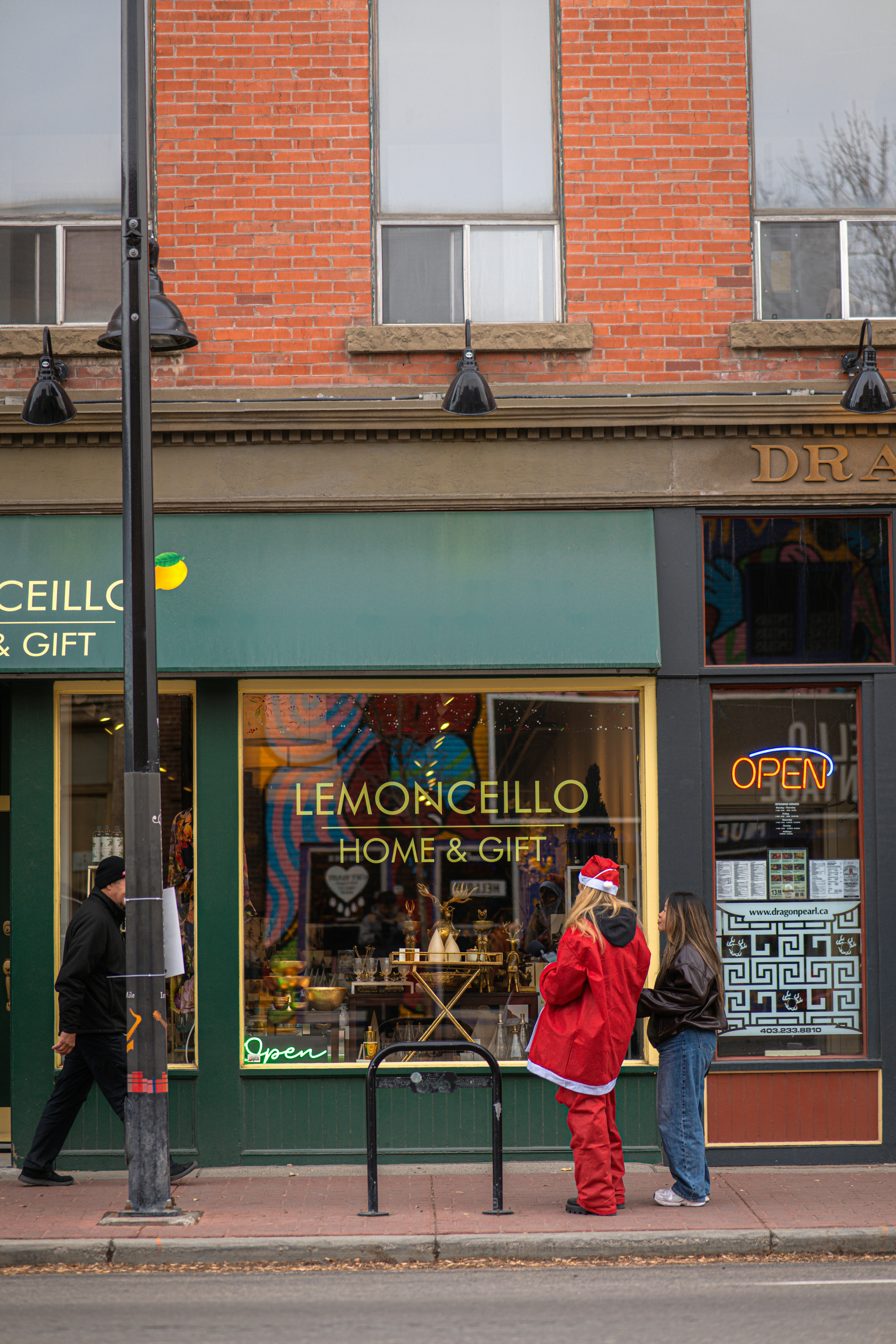 People in santa outfits by a store window.