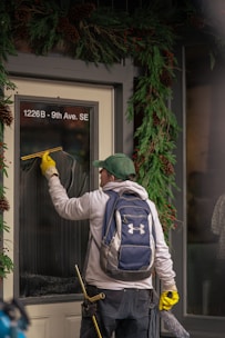 Man cleaning a storefront window with a squeegee.