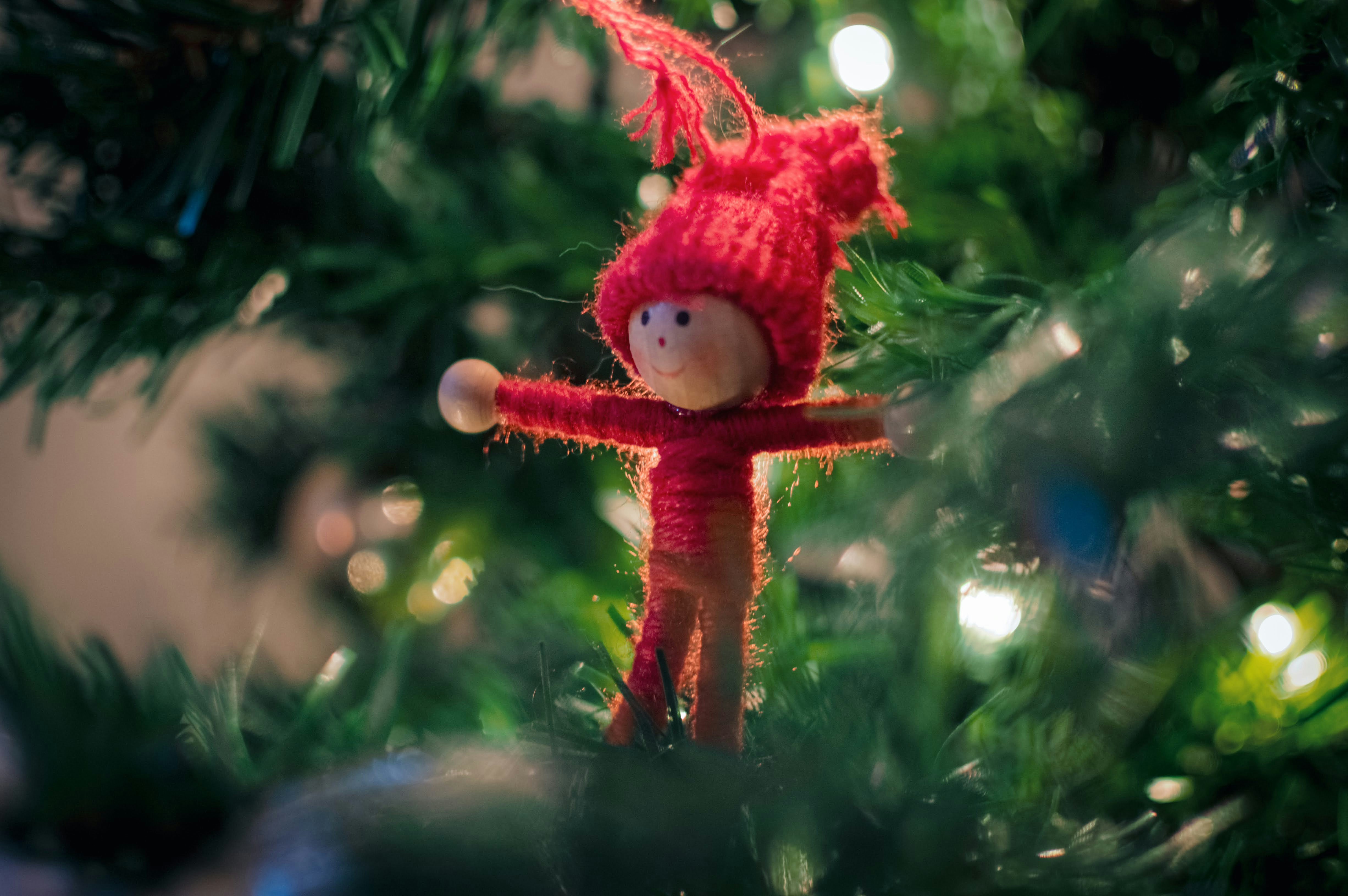 A small doll ornament on a christmas tree.