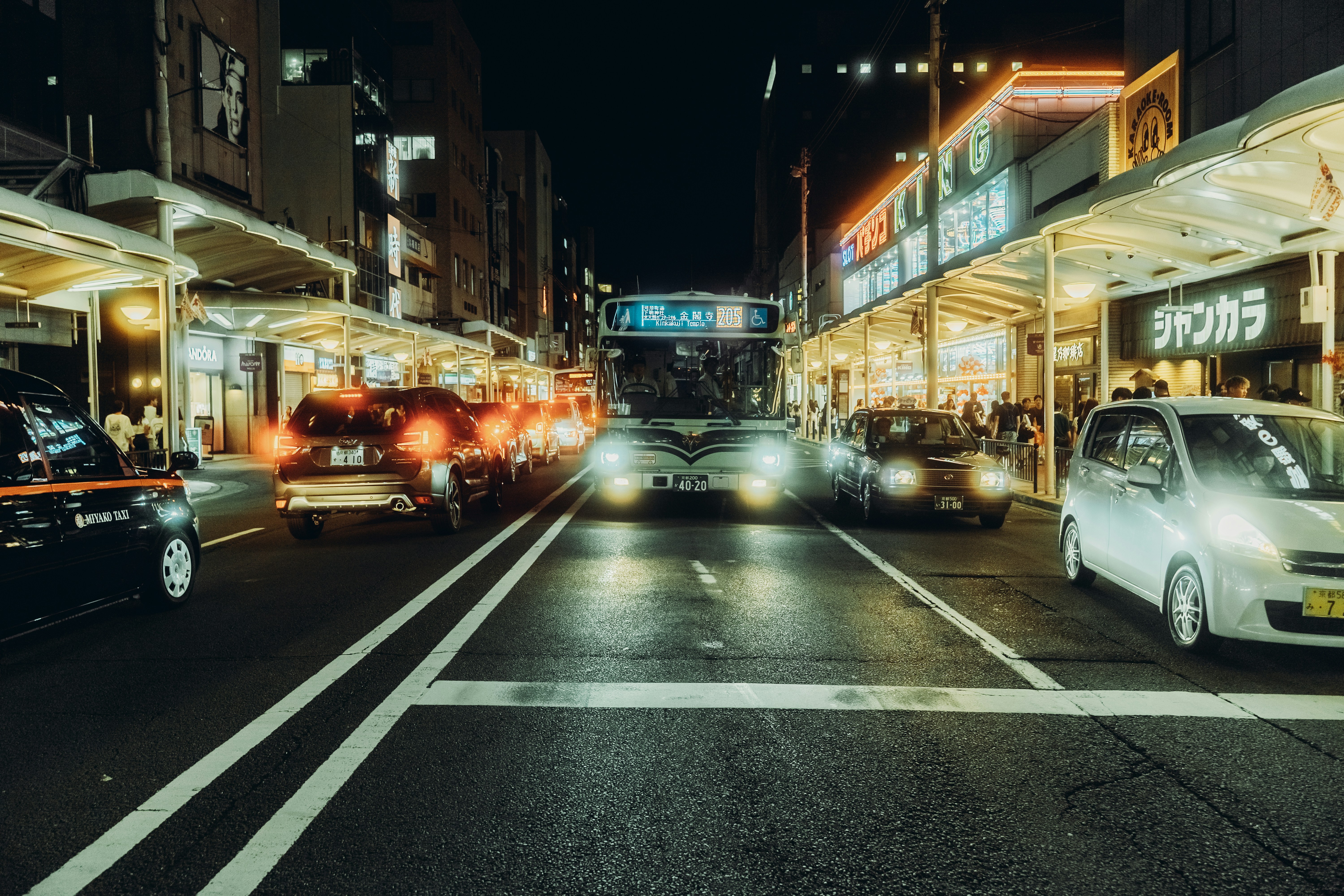 A bus and cars on a city street at night.