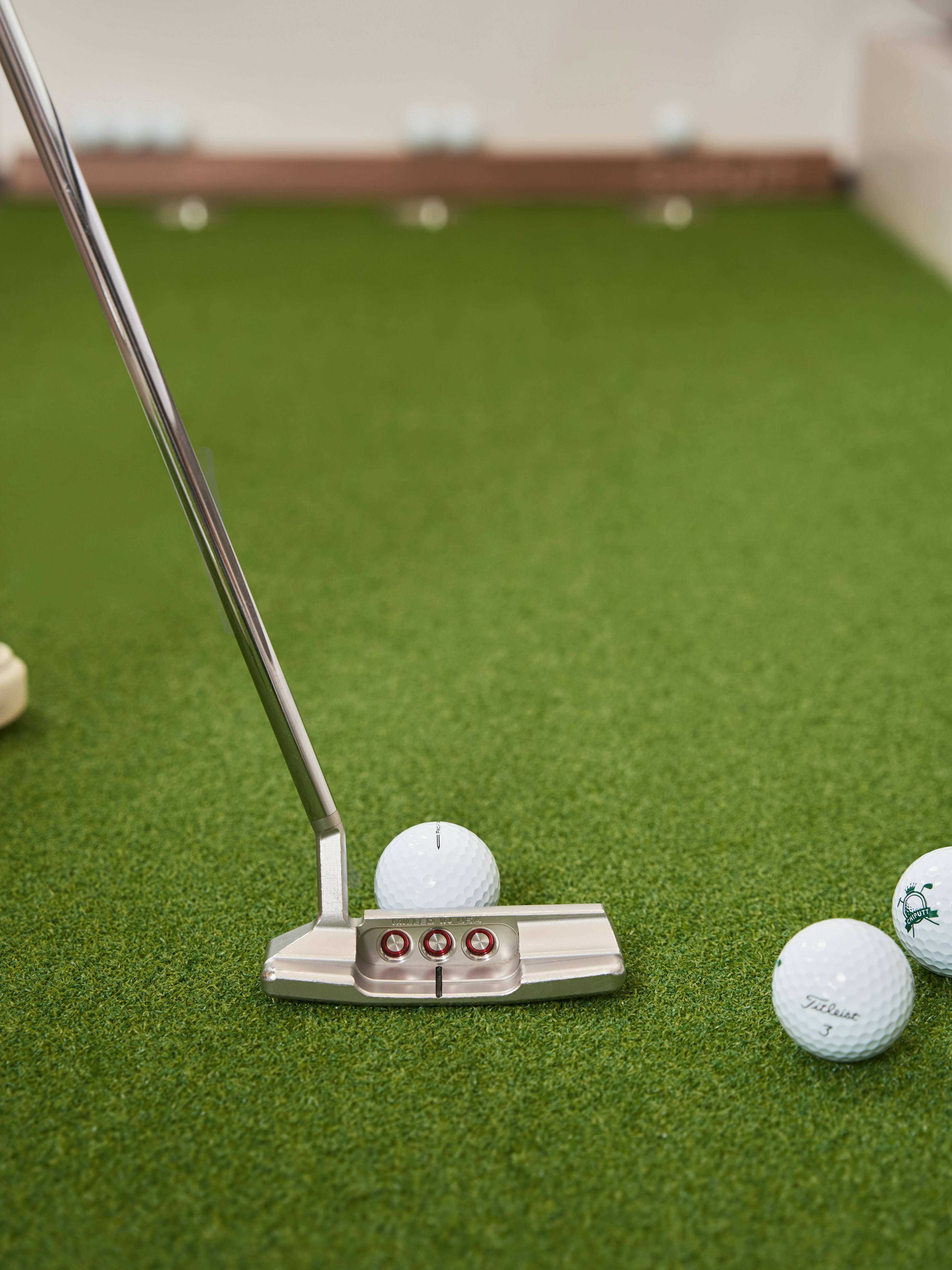 Golf putter and balls on green artificial turf.