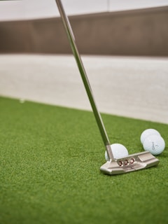Golf putter and balls on artificial turf.