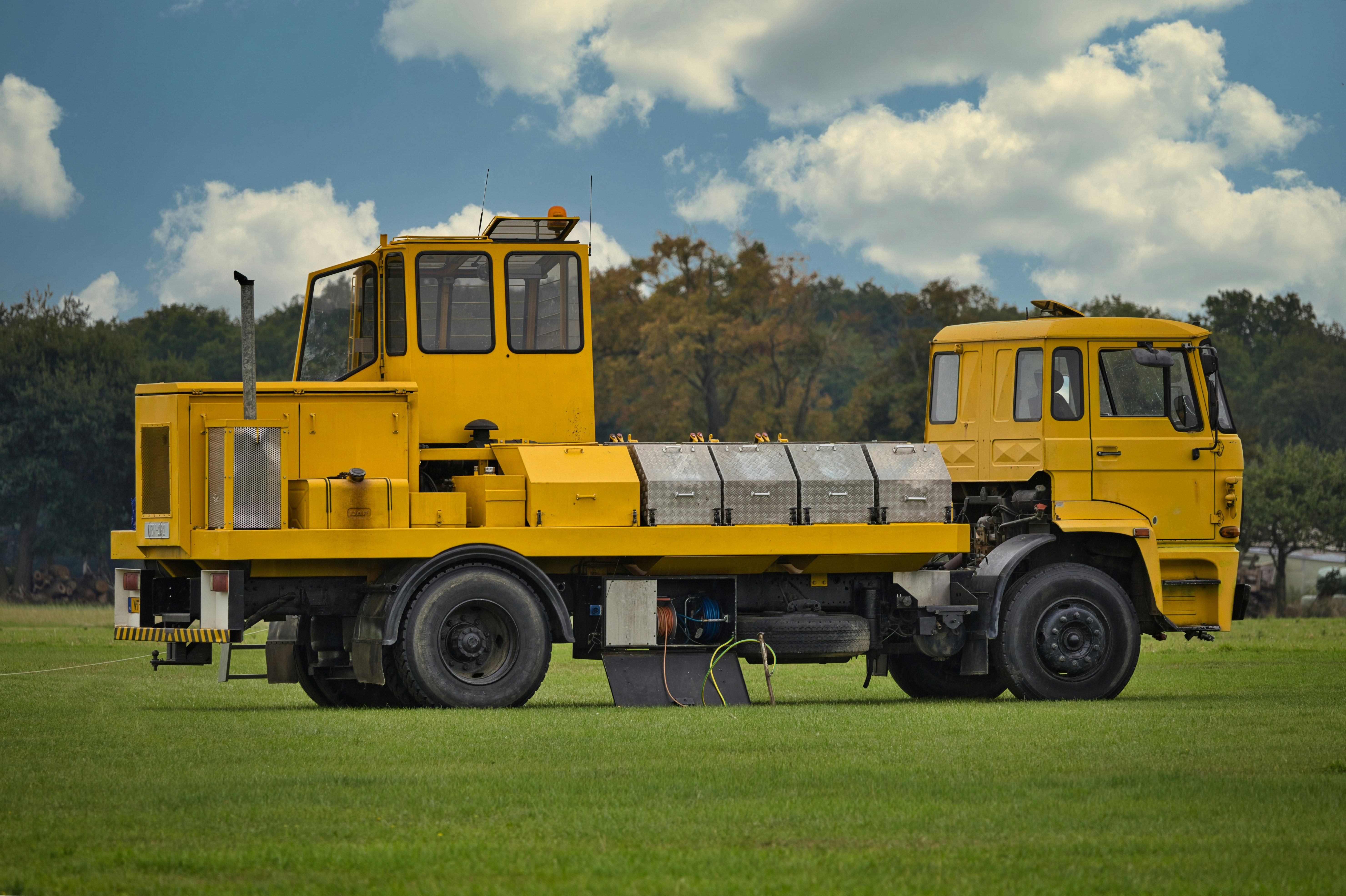 A yellow specialized truck on a grassy field.