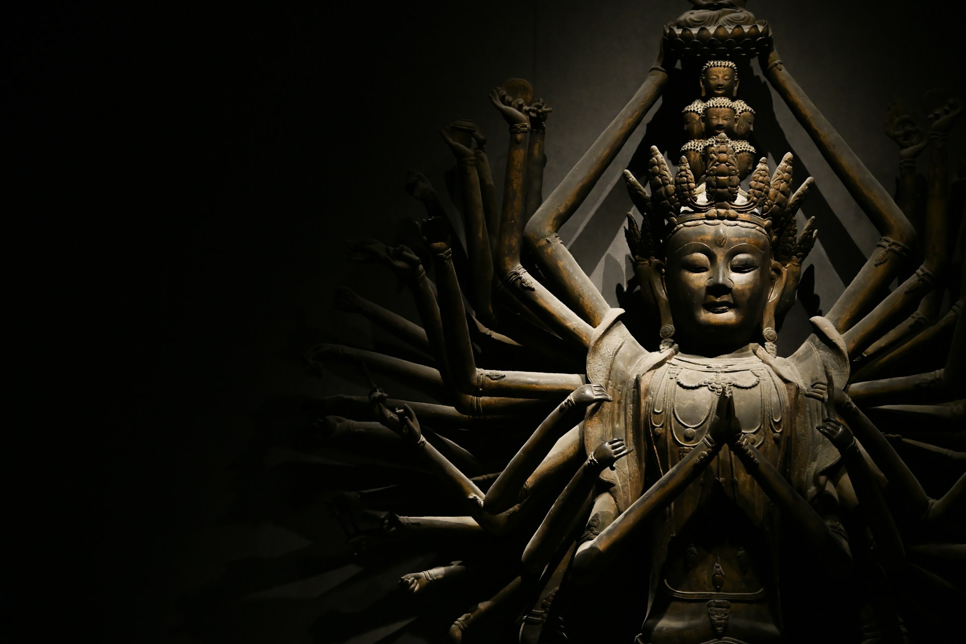 Buddha statue with many arms in dim light