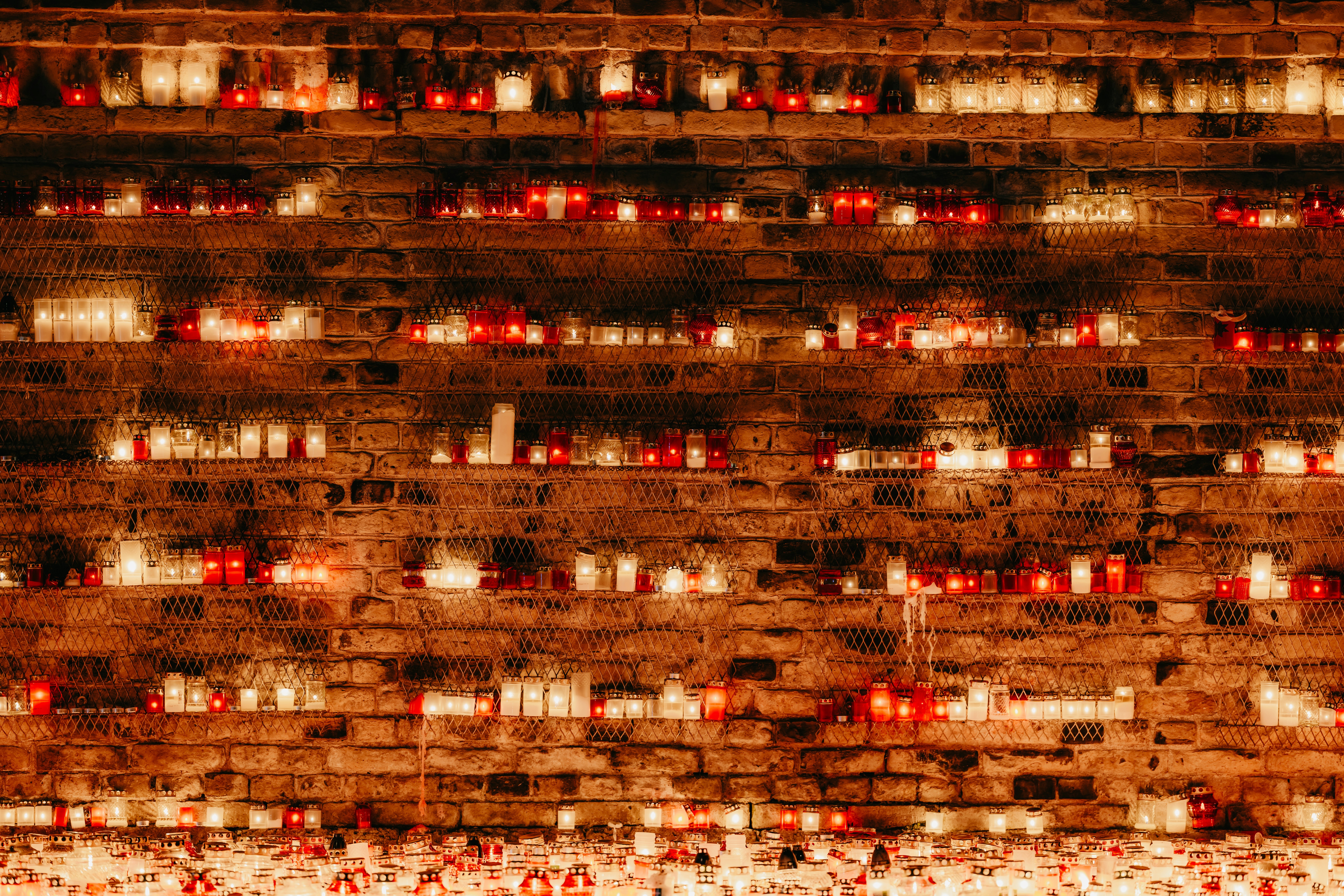 Rows of lit candles on a brick wall