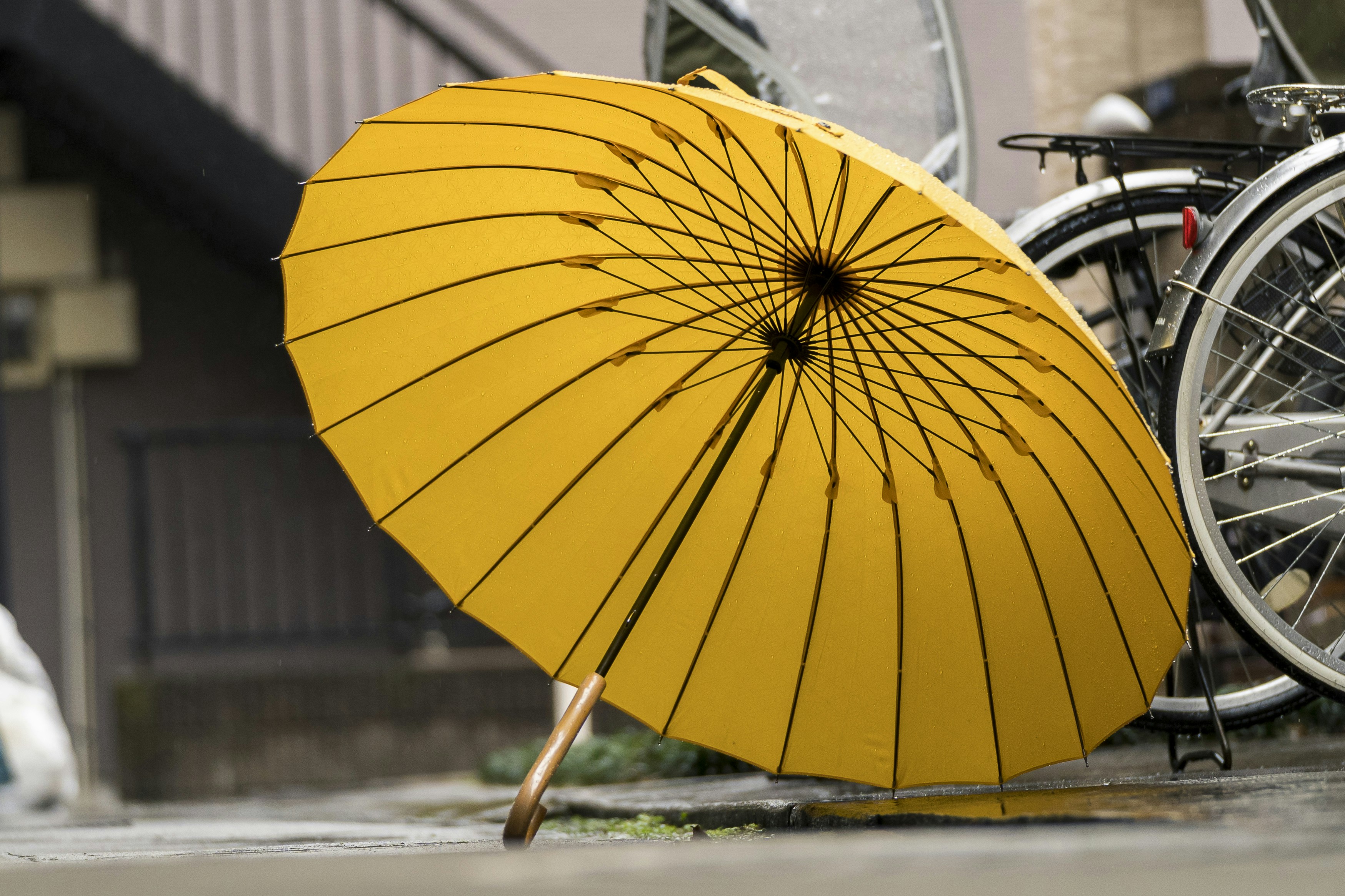 A bright yellow umbrella leaning on bicycles