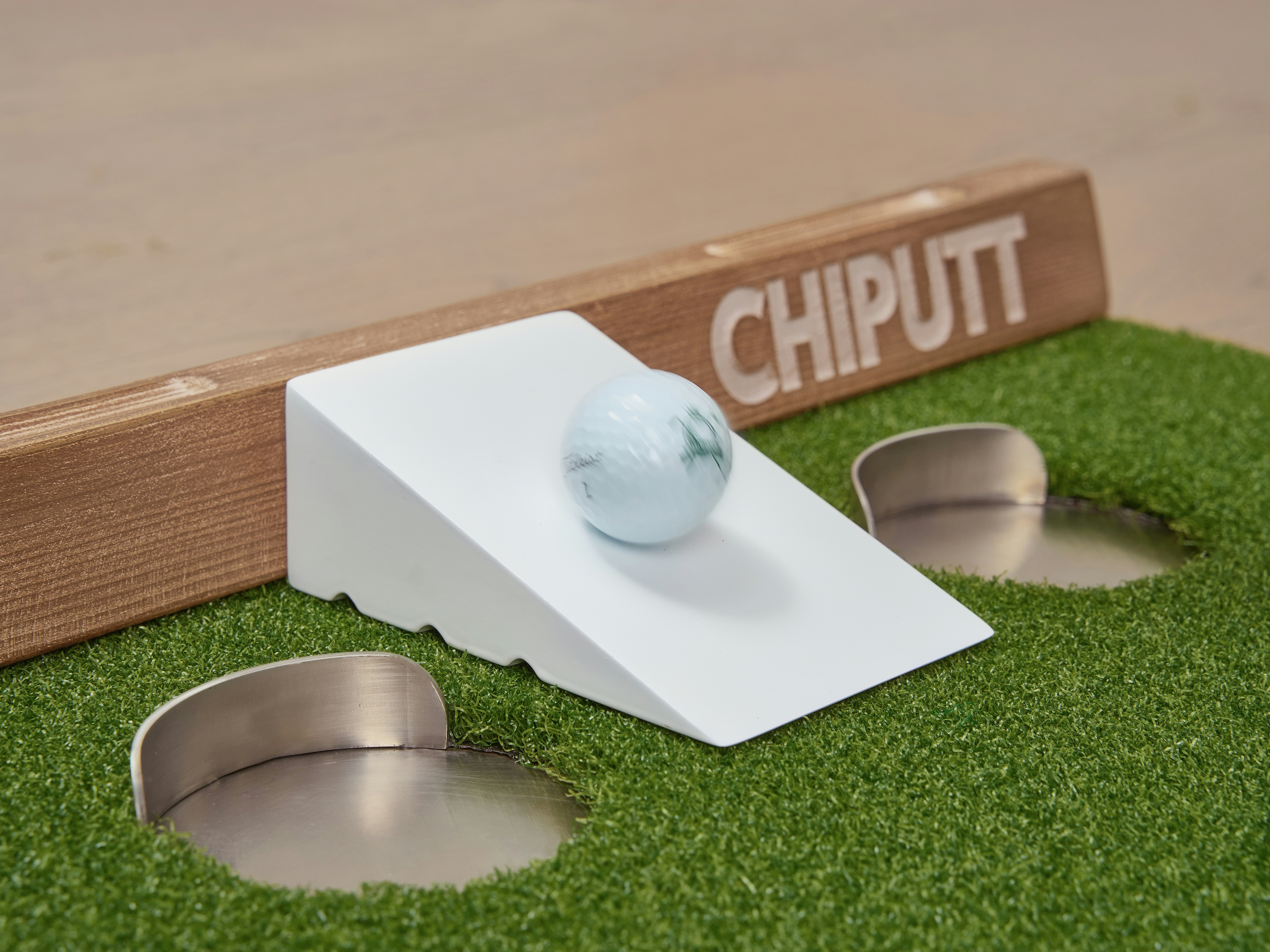 Golf ball on ramp near putting holes