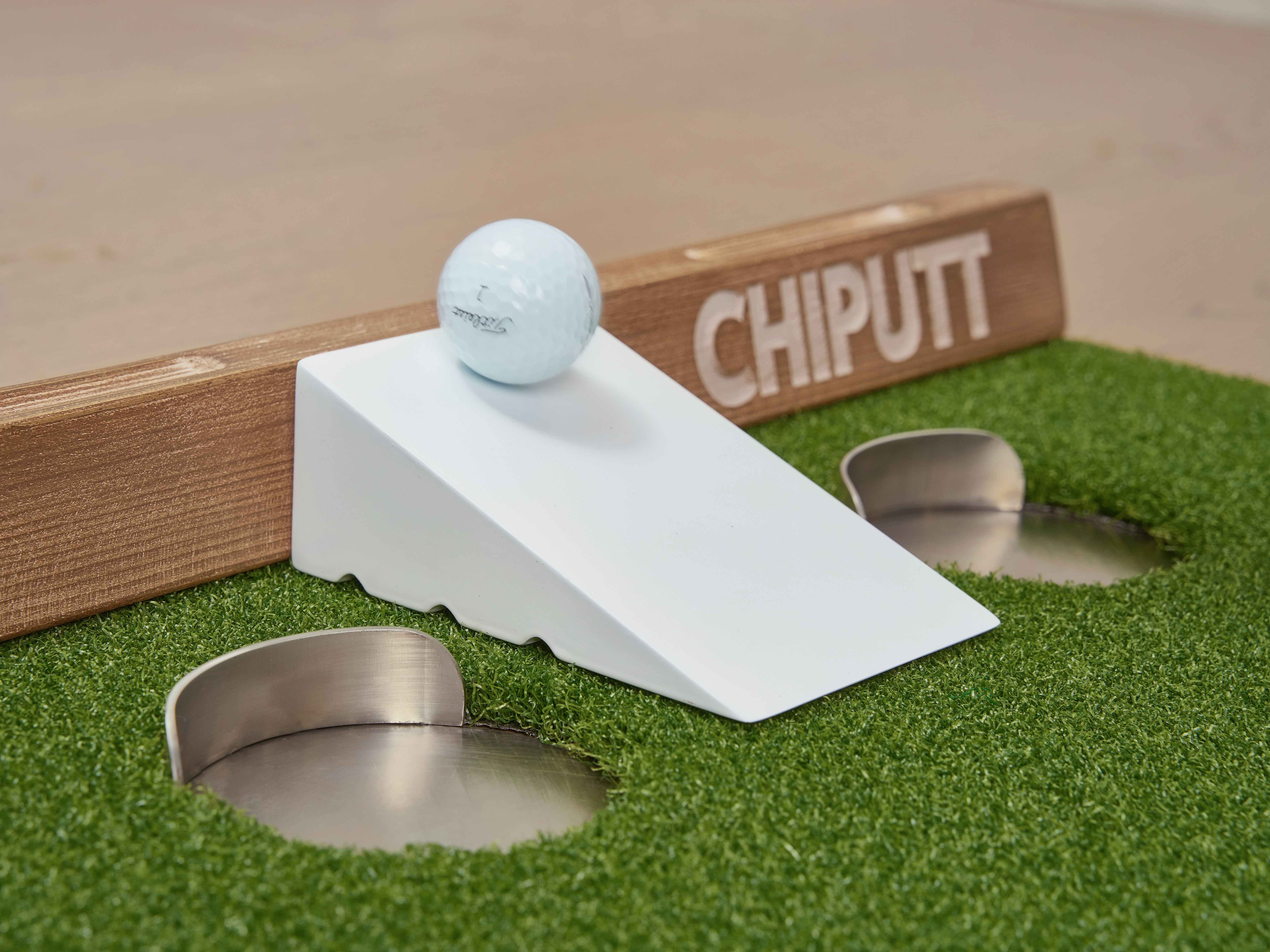 Golf ball on ramp near putting holes