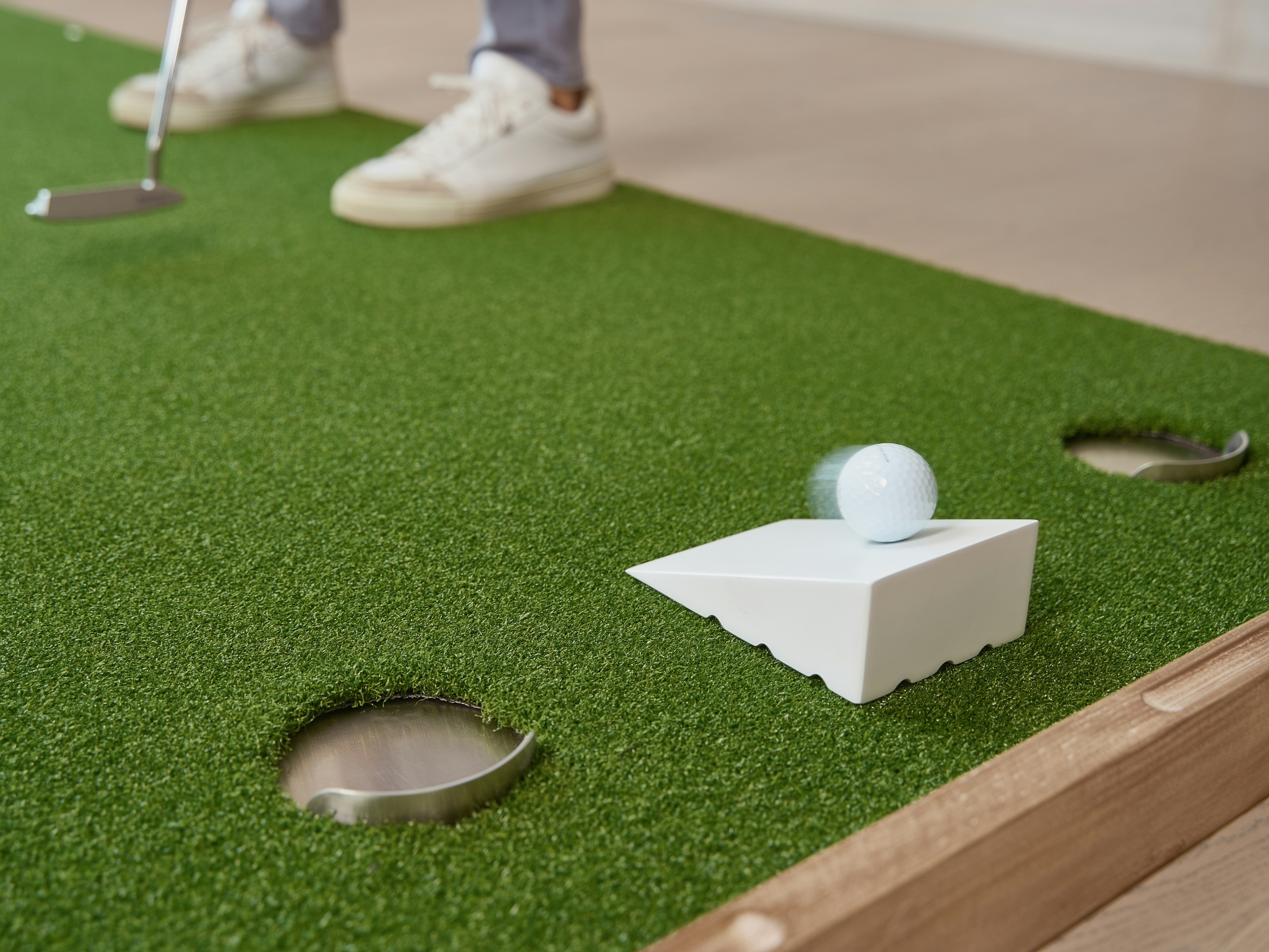 Golfer putting a ball on a miniature golf course.