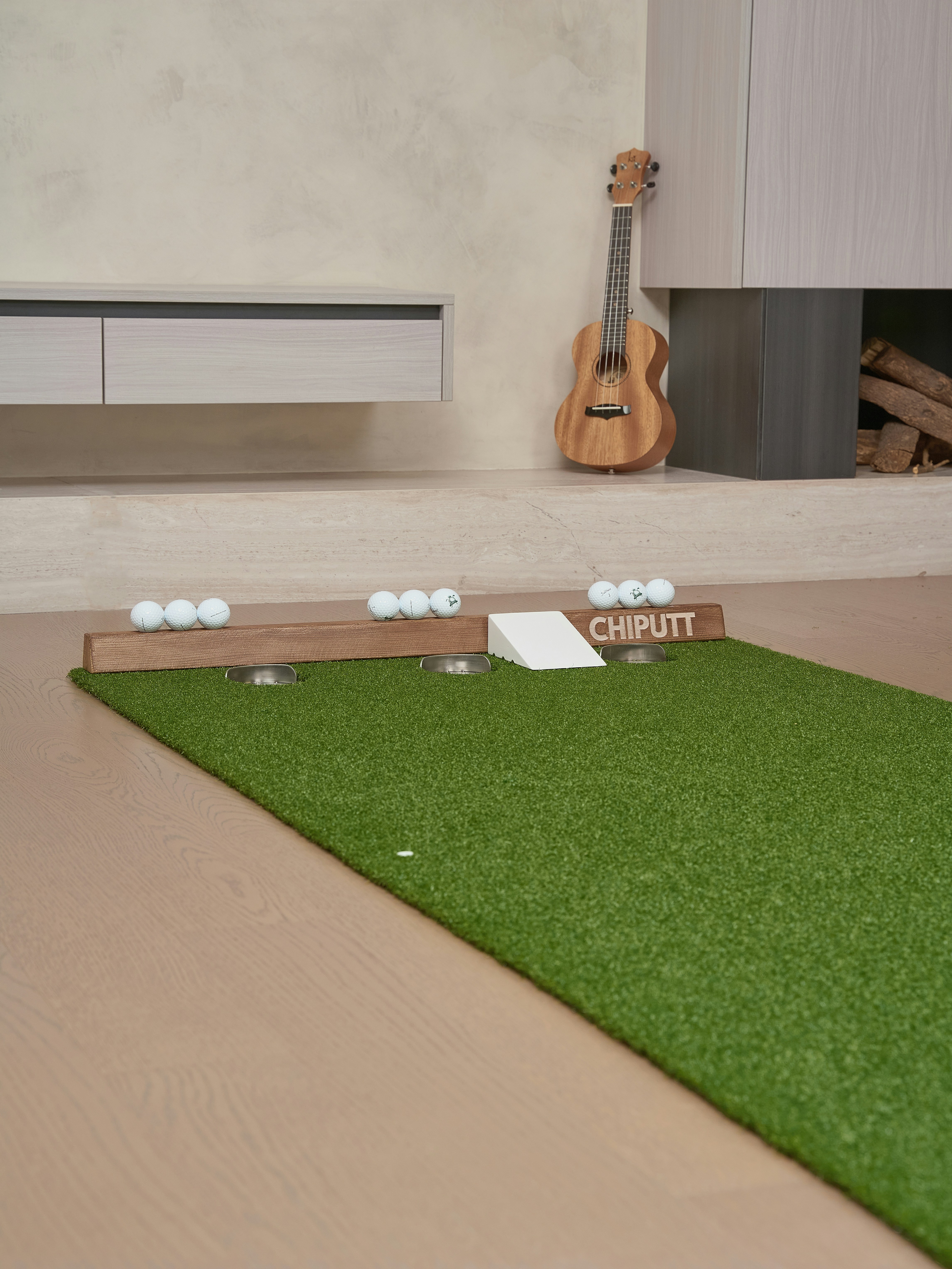 Indoor putting green with golf balls and ukulele.