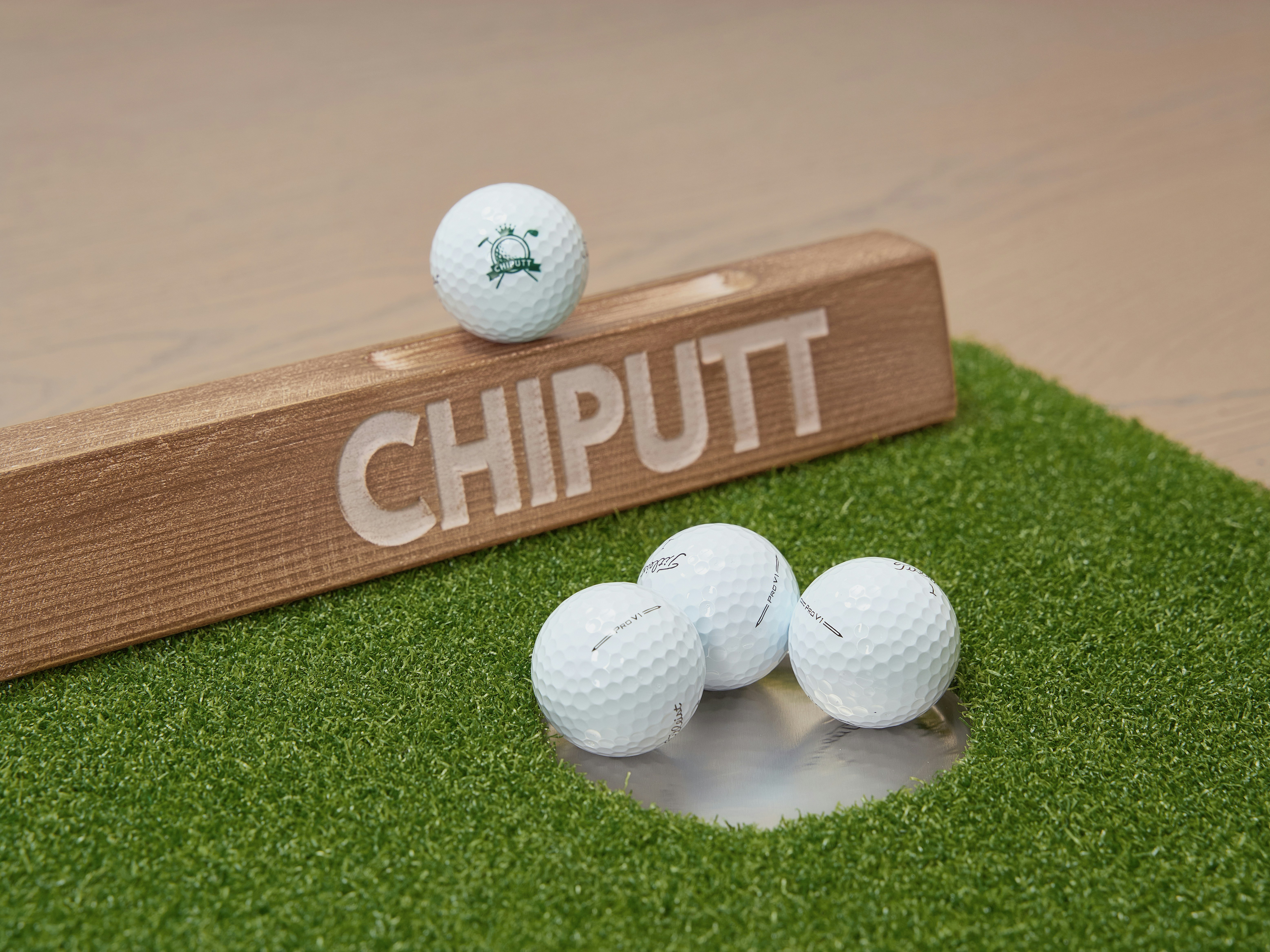 Golf balls on a putting green with a chiputt sign