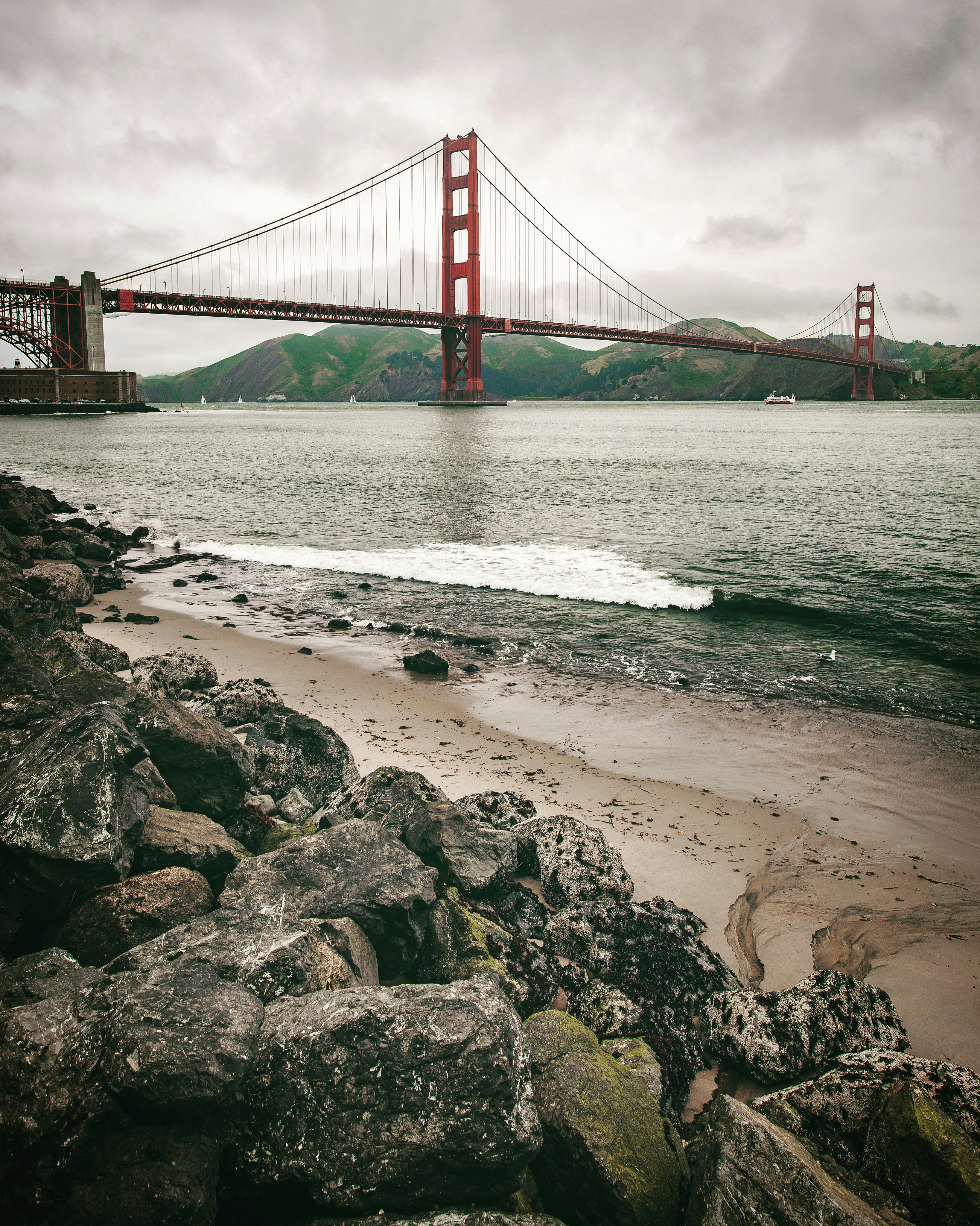 The Golden Gate Bridge spanning the bay above a rocky beach in San Francisco