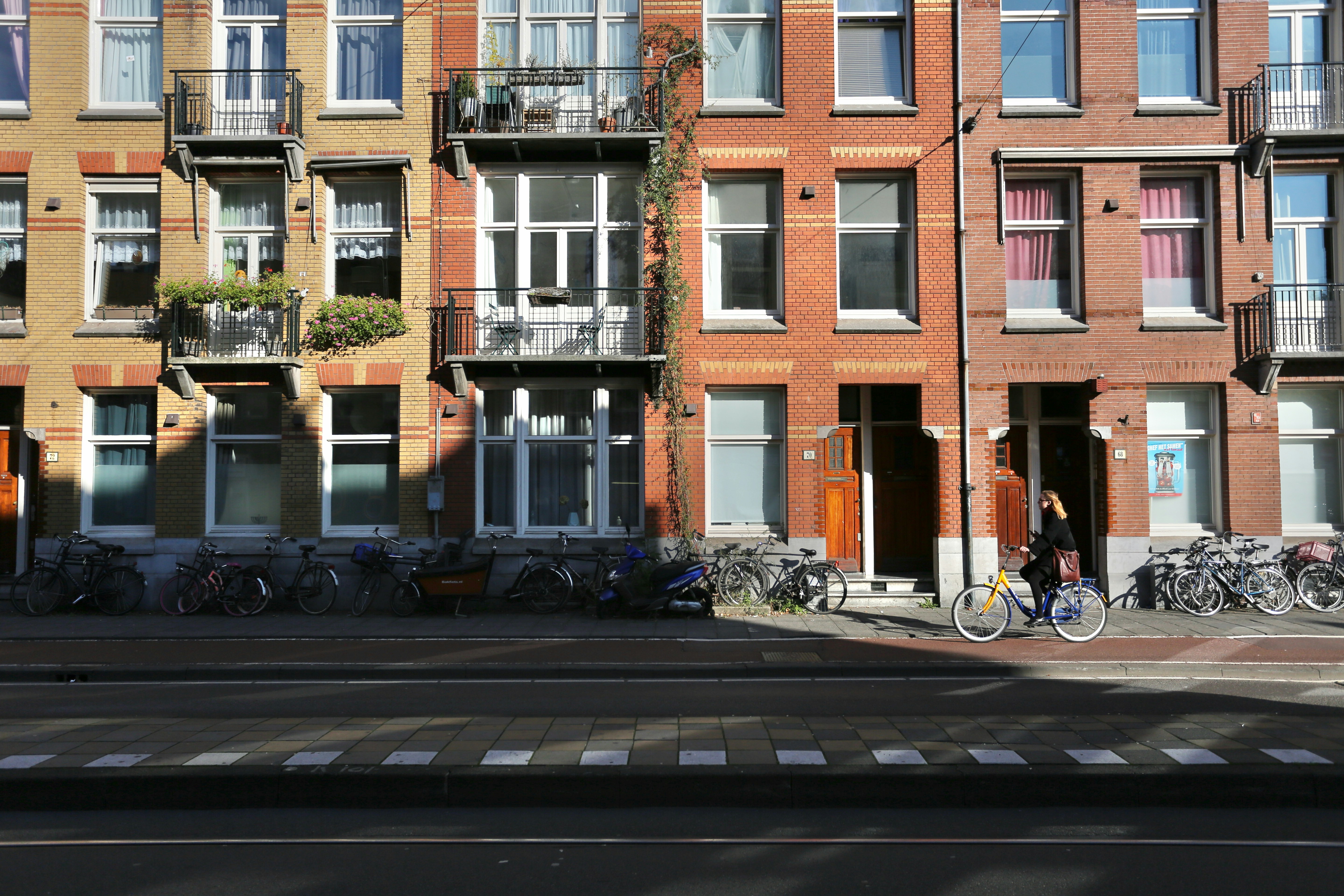 A person cycling past a row of brick apartment buildings with balconies