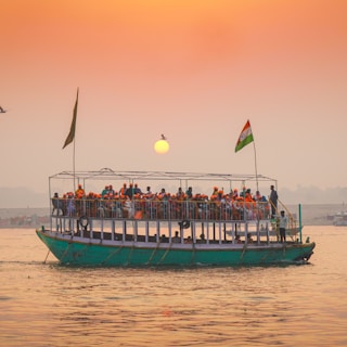 Tour boat filled with people sailing at sunset
