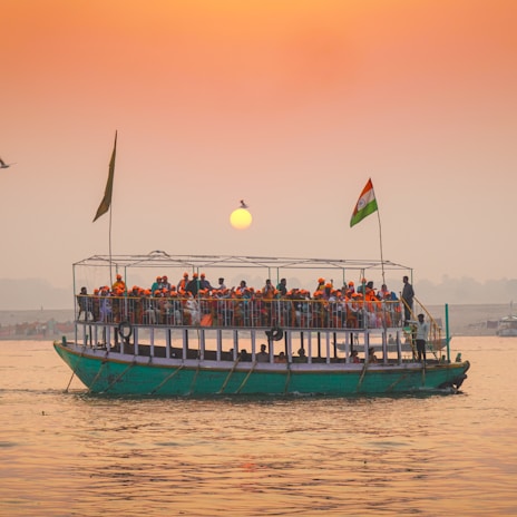 Tour boat filled with people sailing at sunset