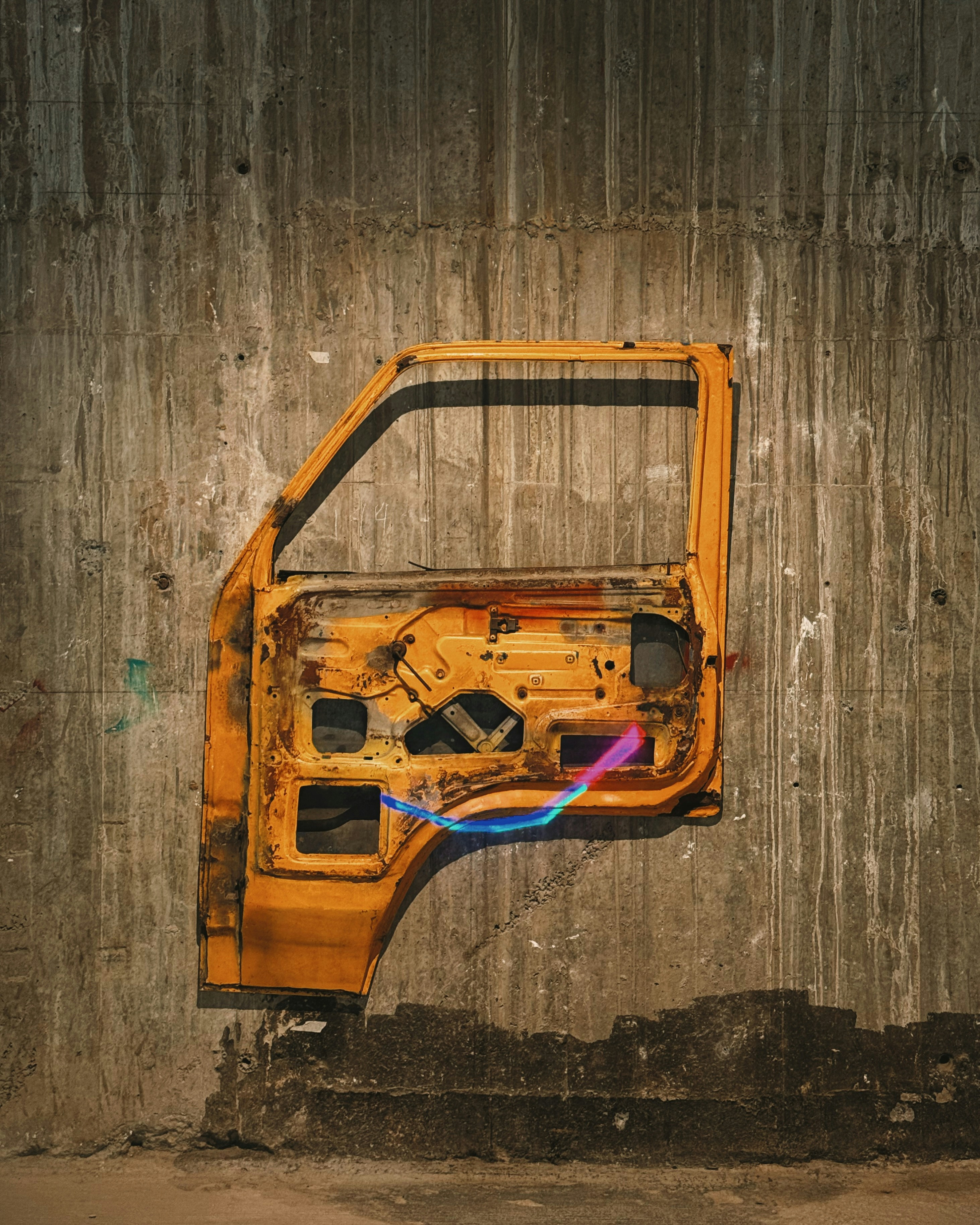 Rusty yellow car door against concrete wall