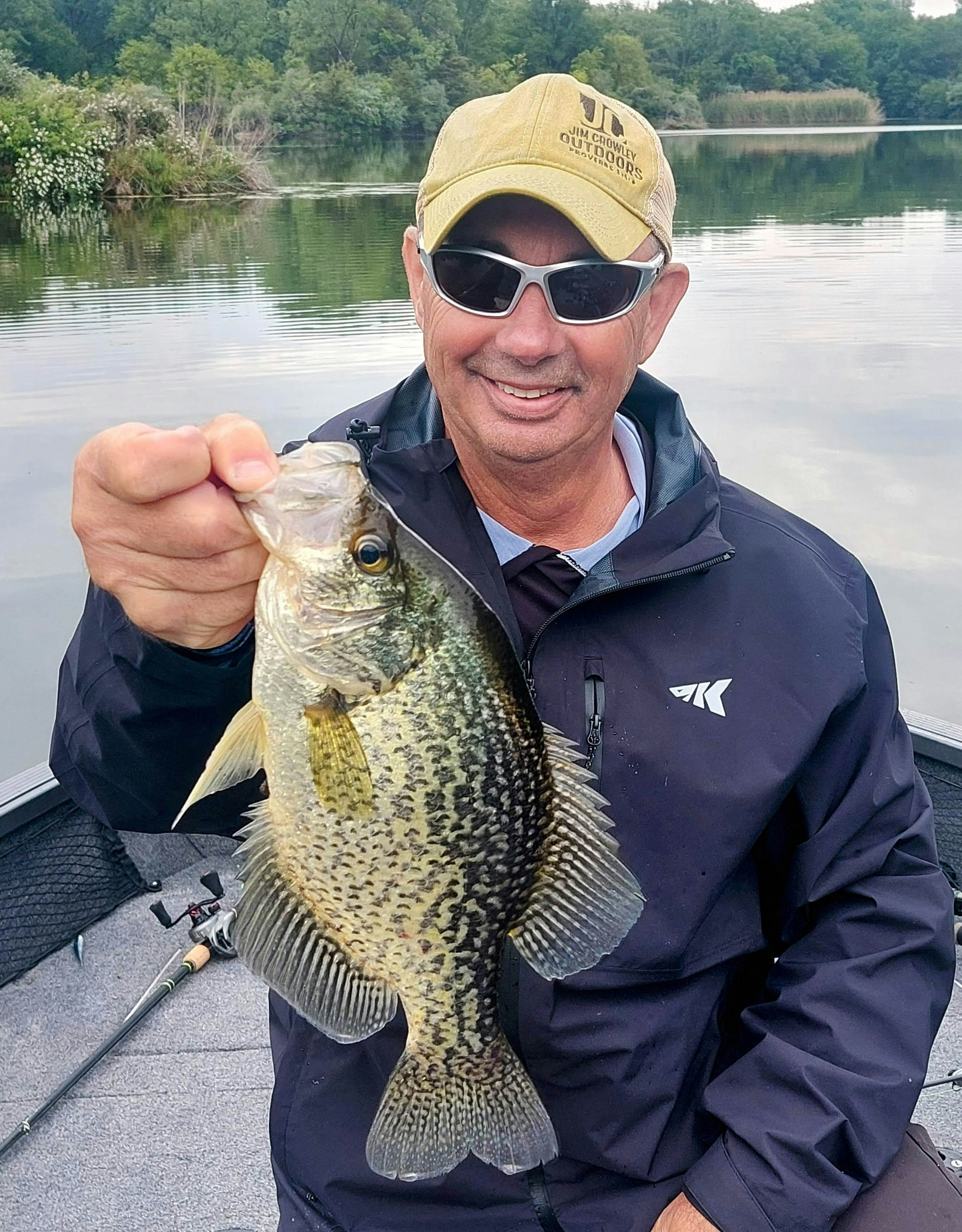 Man holding a large crappie fish on a boat