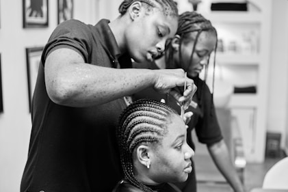 Two women braiding hair in a salon.