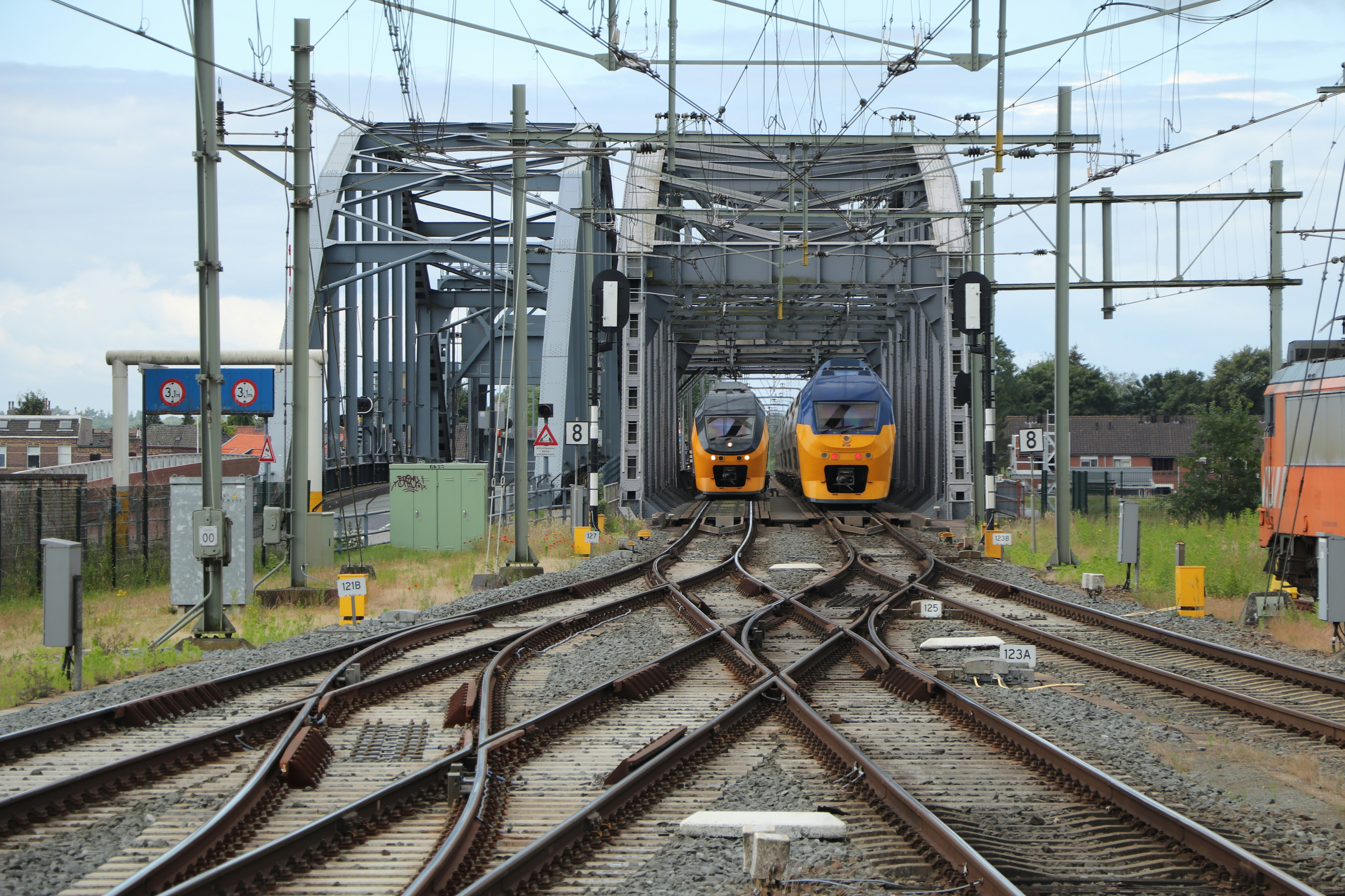 Dos trenes amarillos acercándose a un cruce de puente