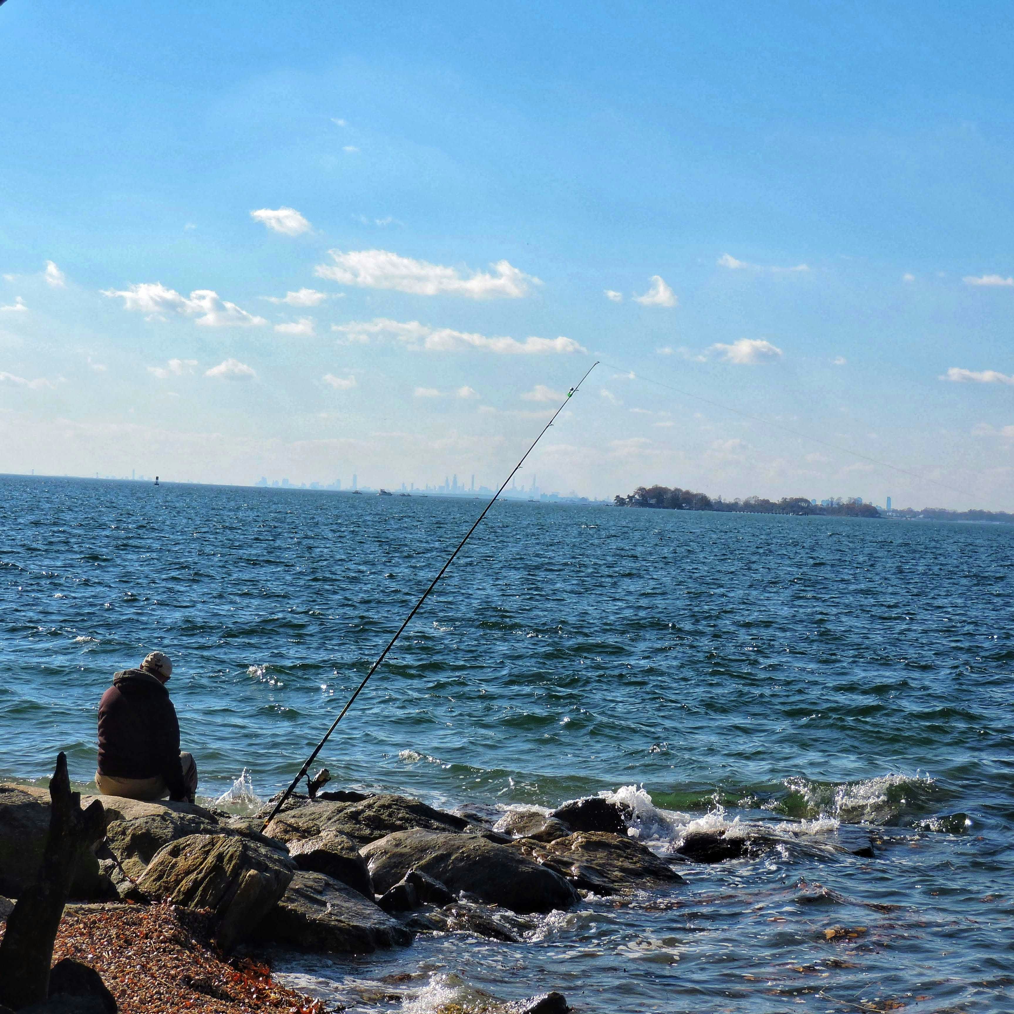 Man fishing on rocky shore with ocean view