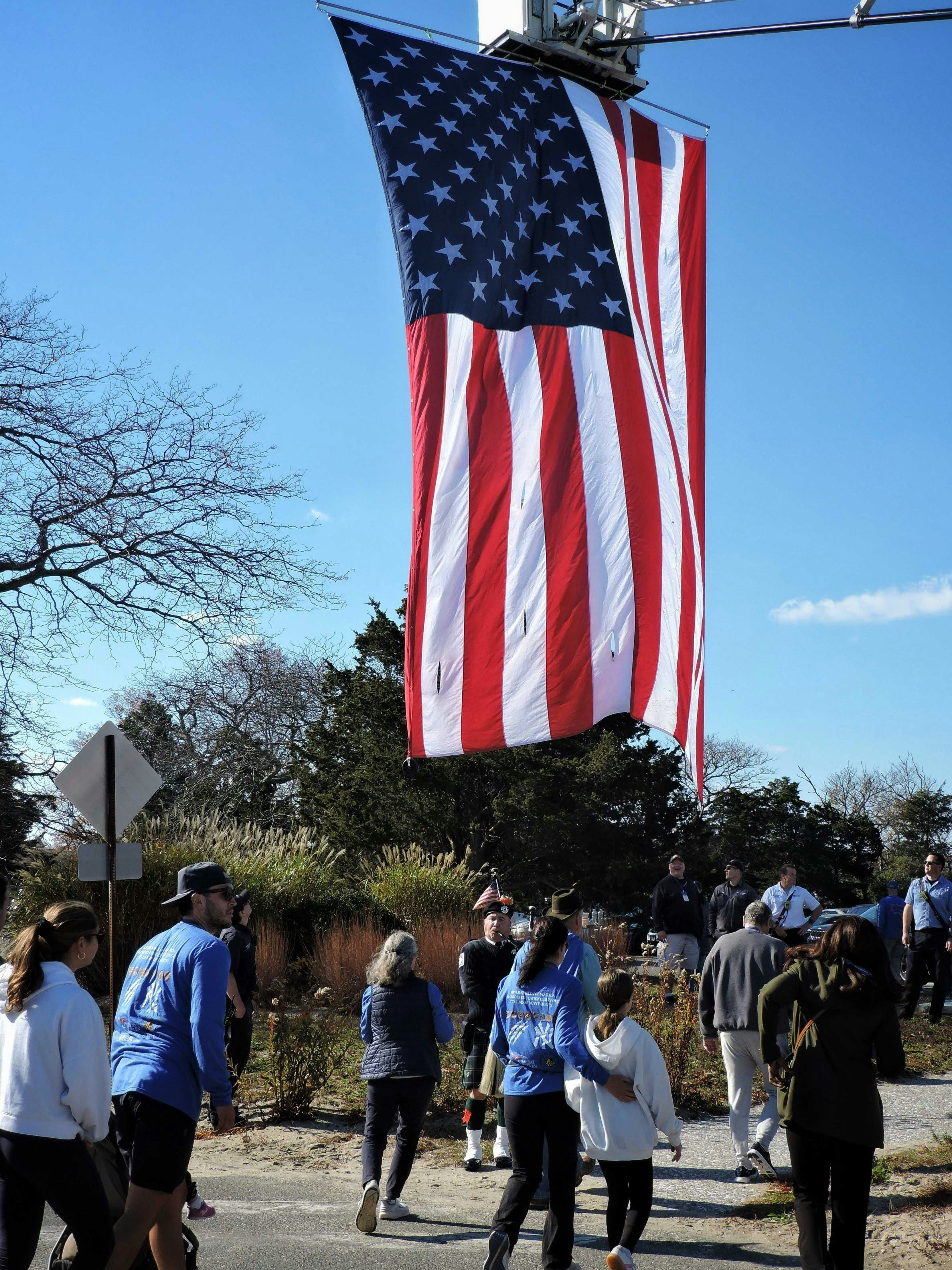 American flag hangs above a crowd outdoors gathering of people