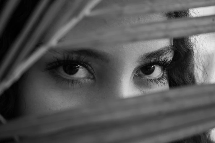 Woman peeking through blinds