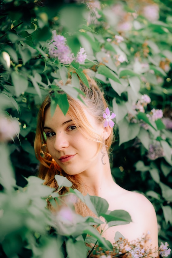 Young woman with flower in hair among green leaves