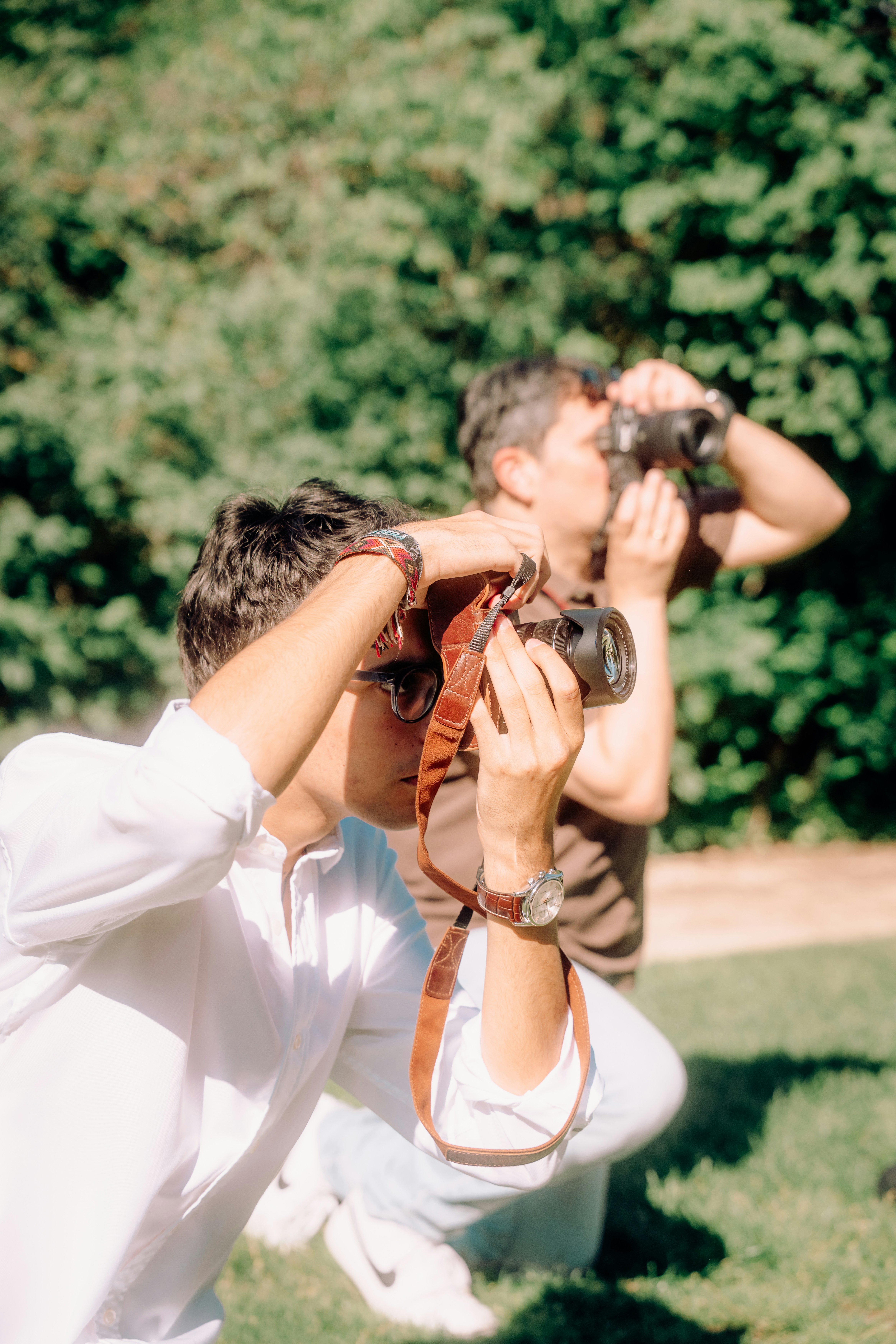 Two men crouching and taking photos with cameras.