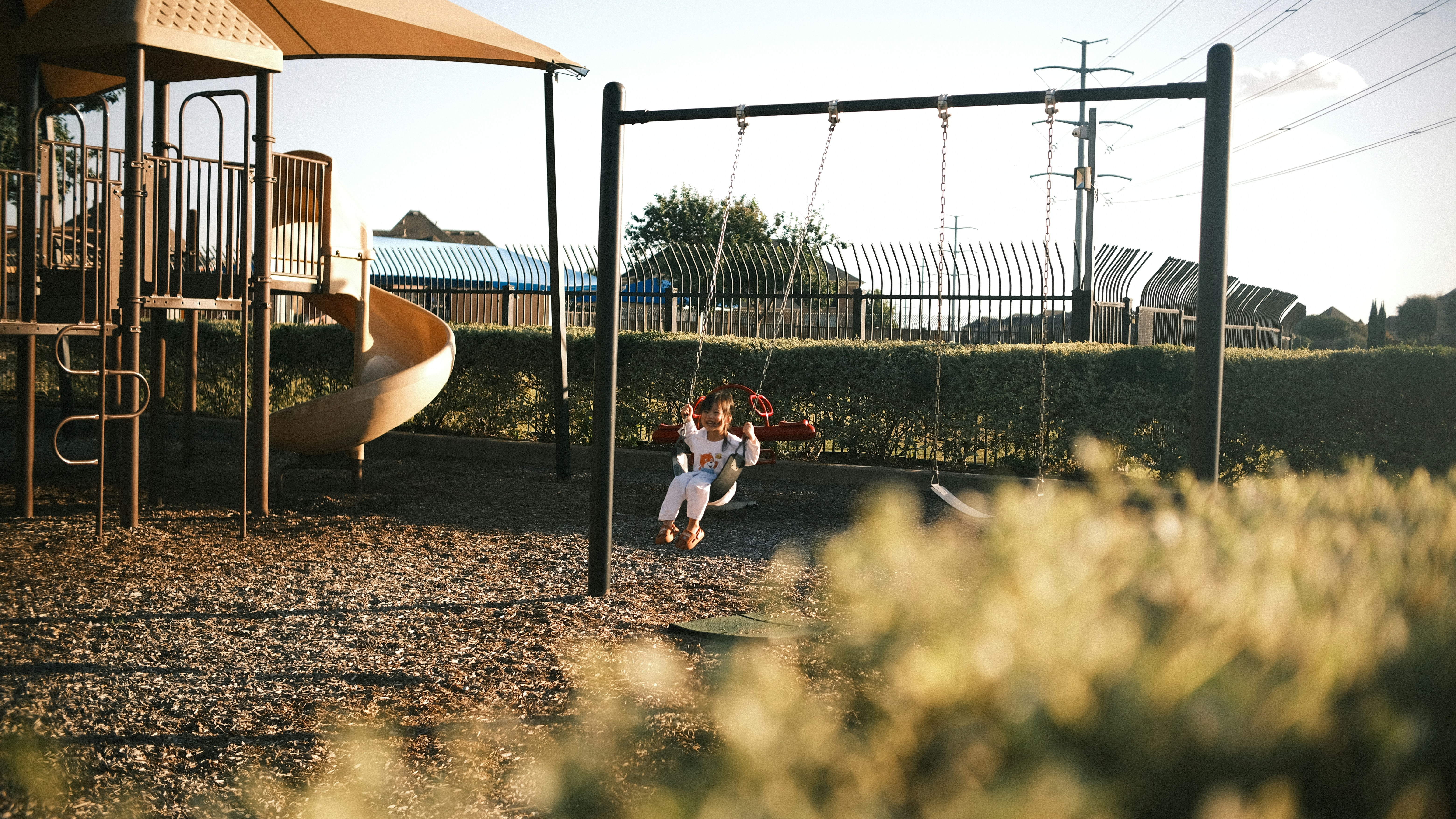 Children swinging on playground equipment at sunset