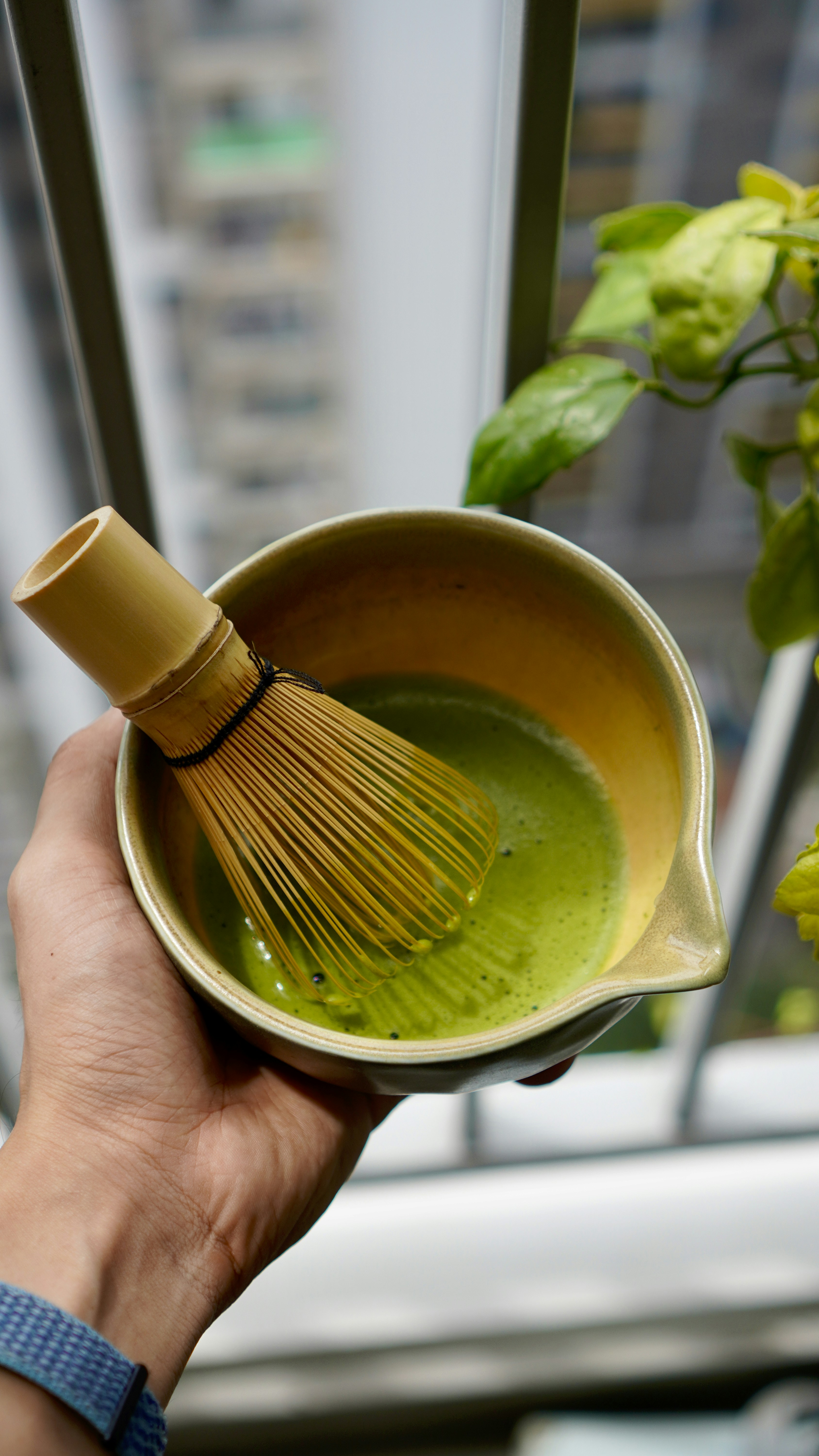 Hand holding a matcha bowl with whisk