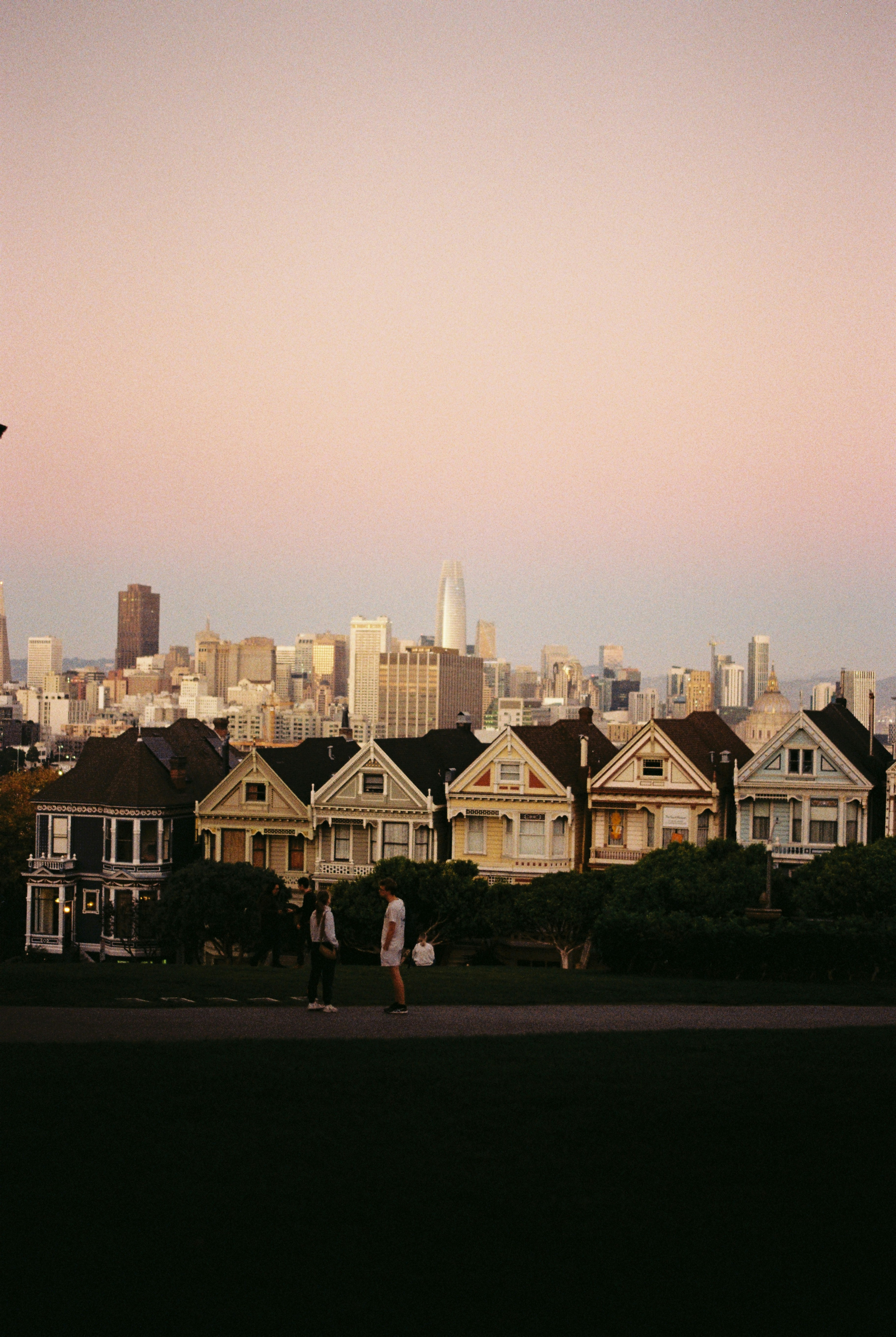 Bemalte viktorianische Häuser mit Skyline der Stadt bei Sonnenuntergang