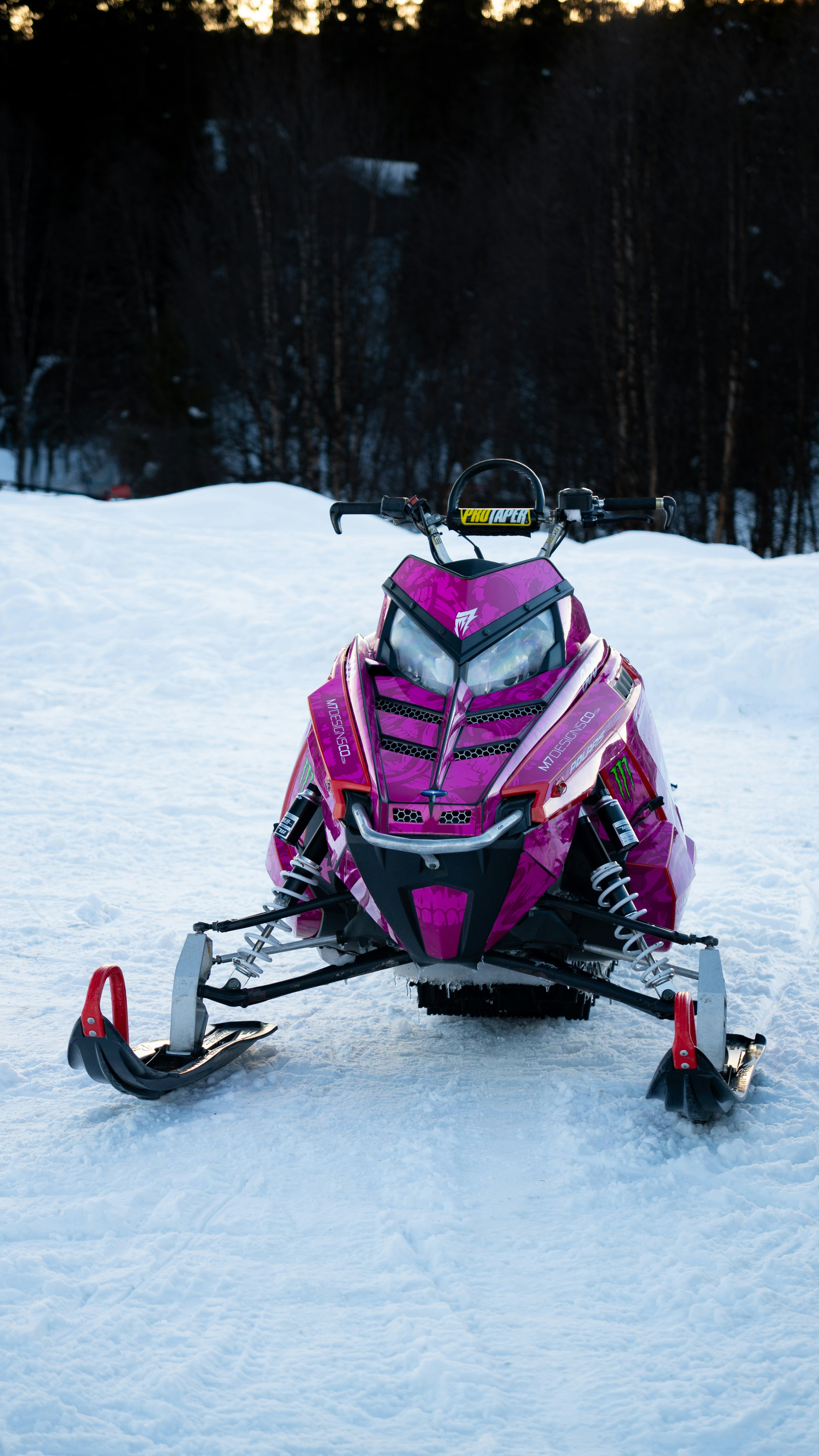 Pink snowmobile parked on a snowy slope