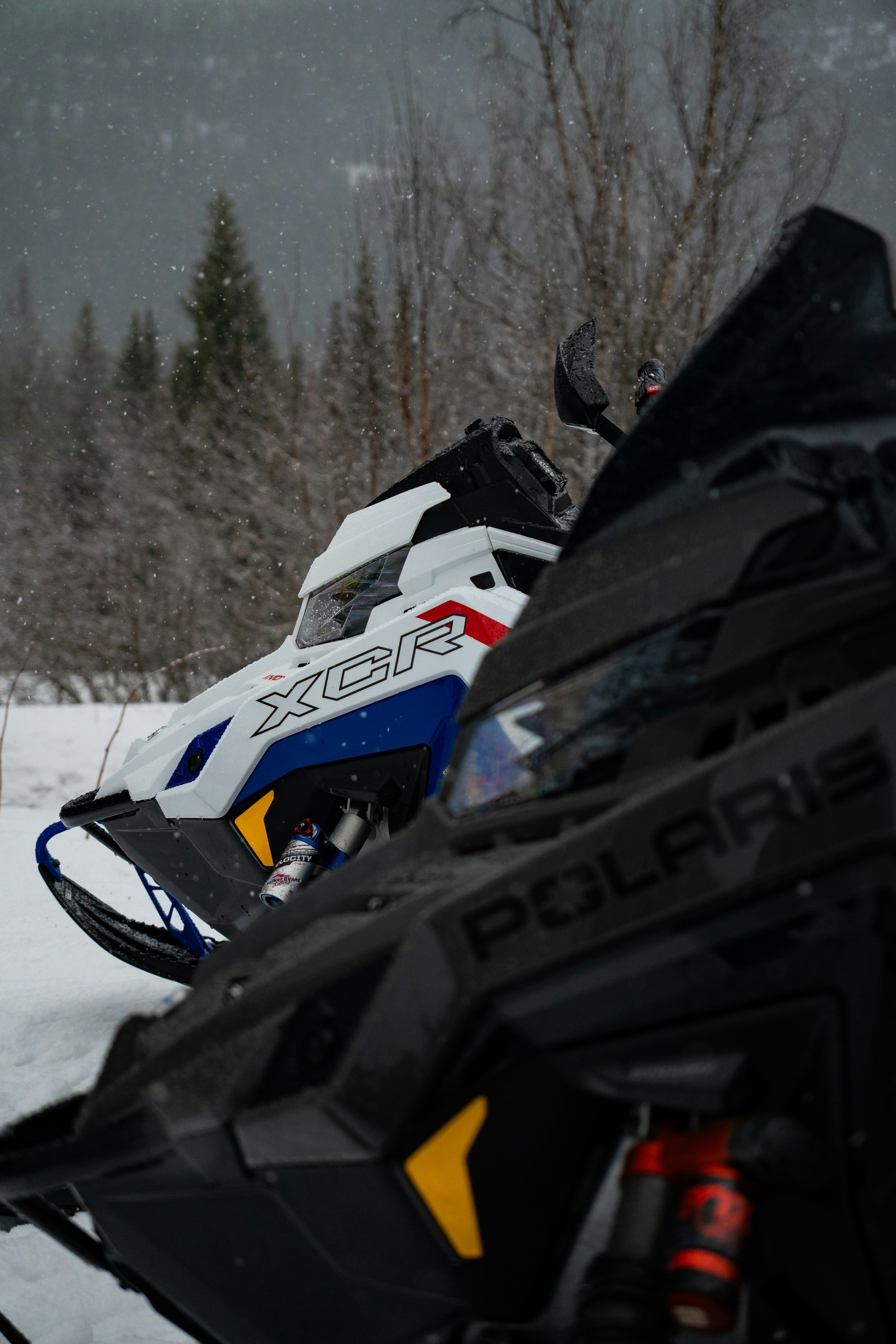 Two snowmobiles parked in a snowy landscape.