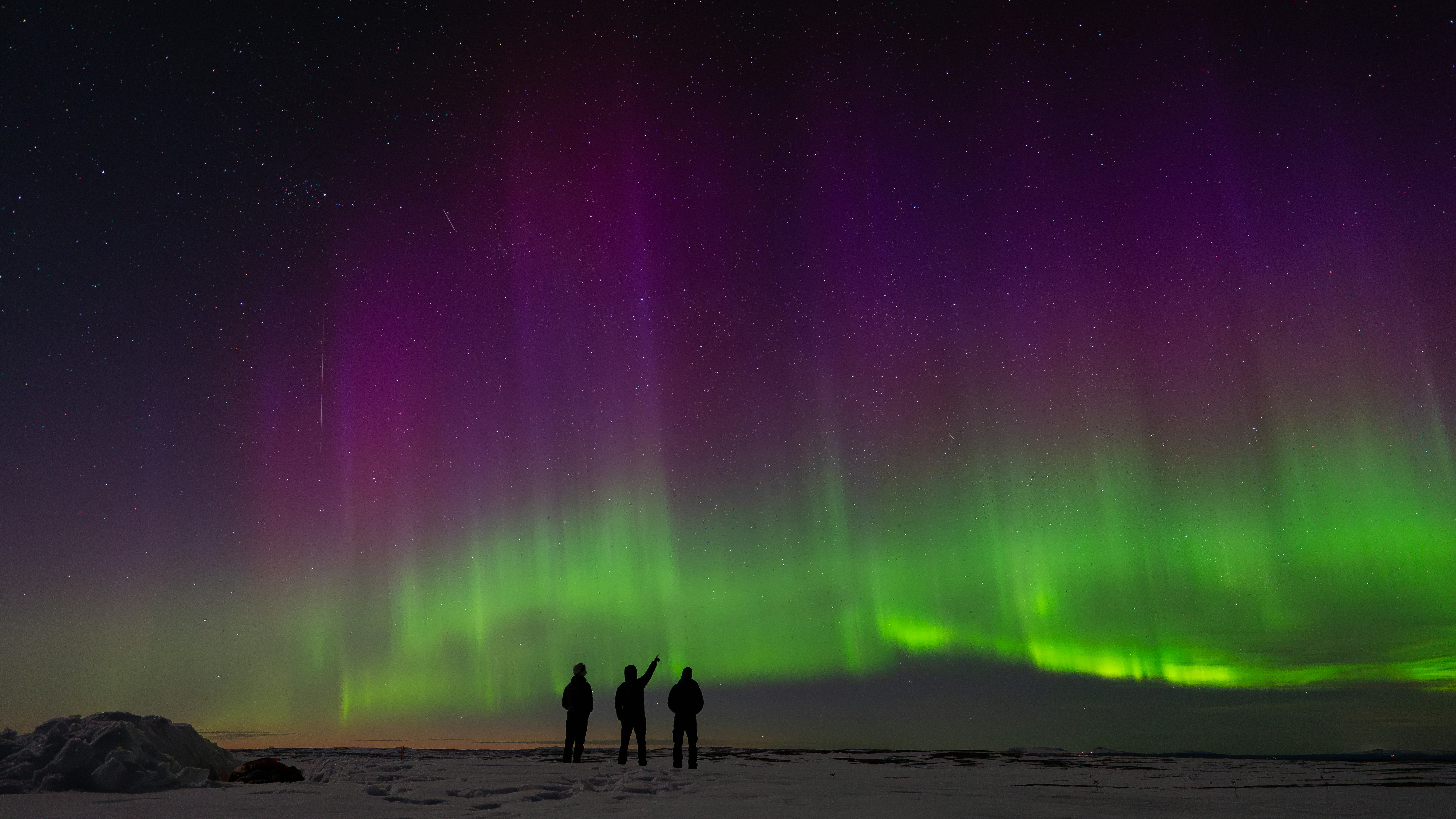 People watching the aurora borealis light up the night sky.