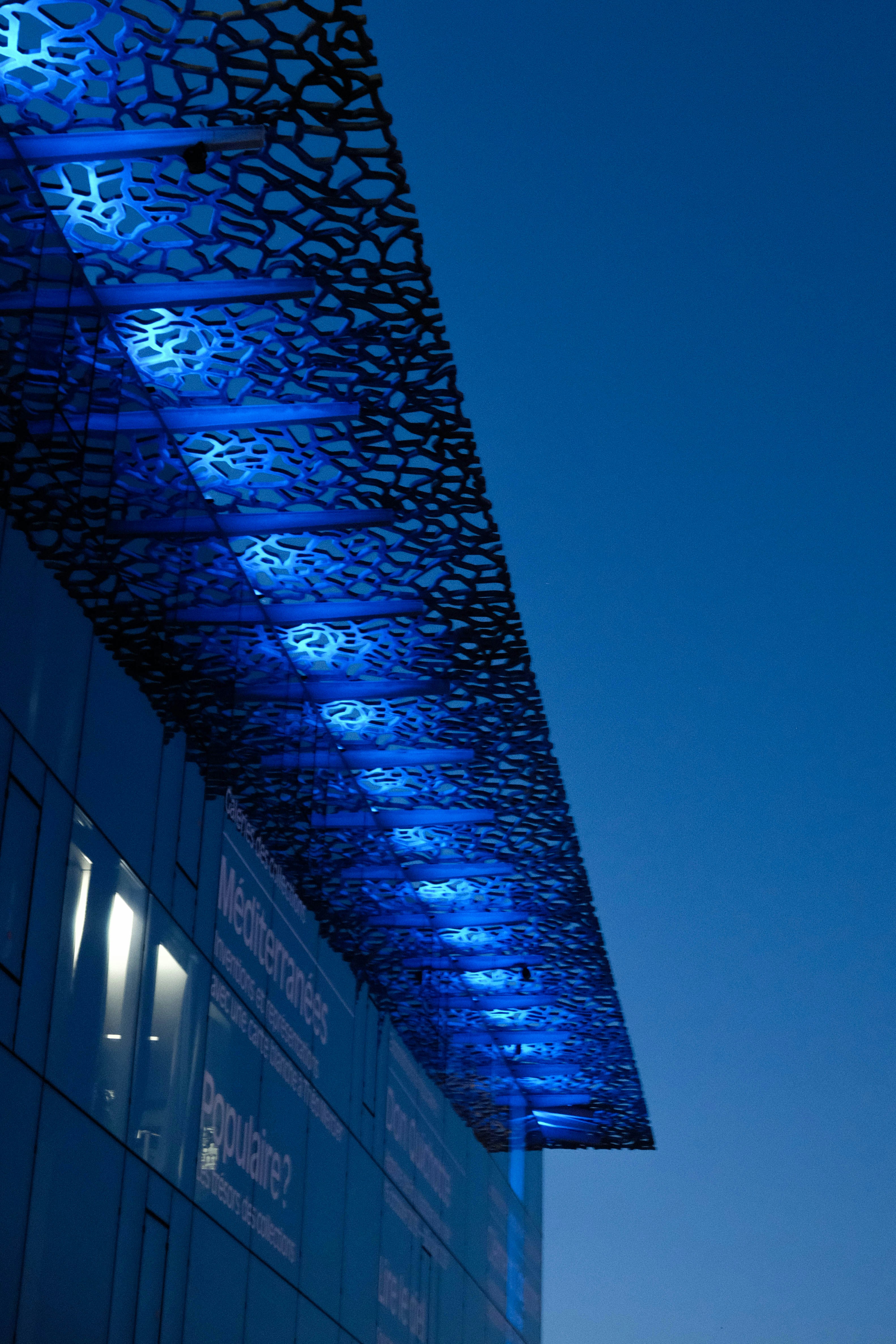 夕暮れ時に青い光が灯るモダンな建物