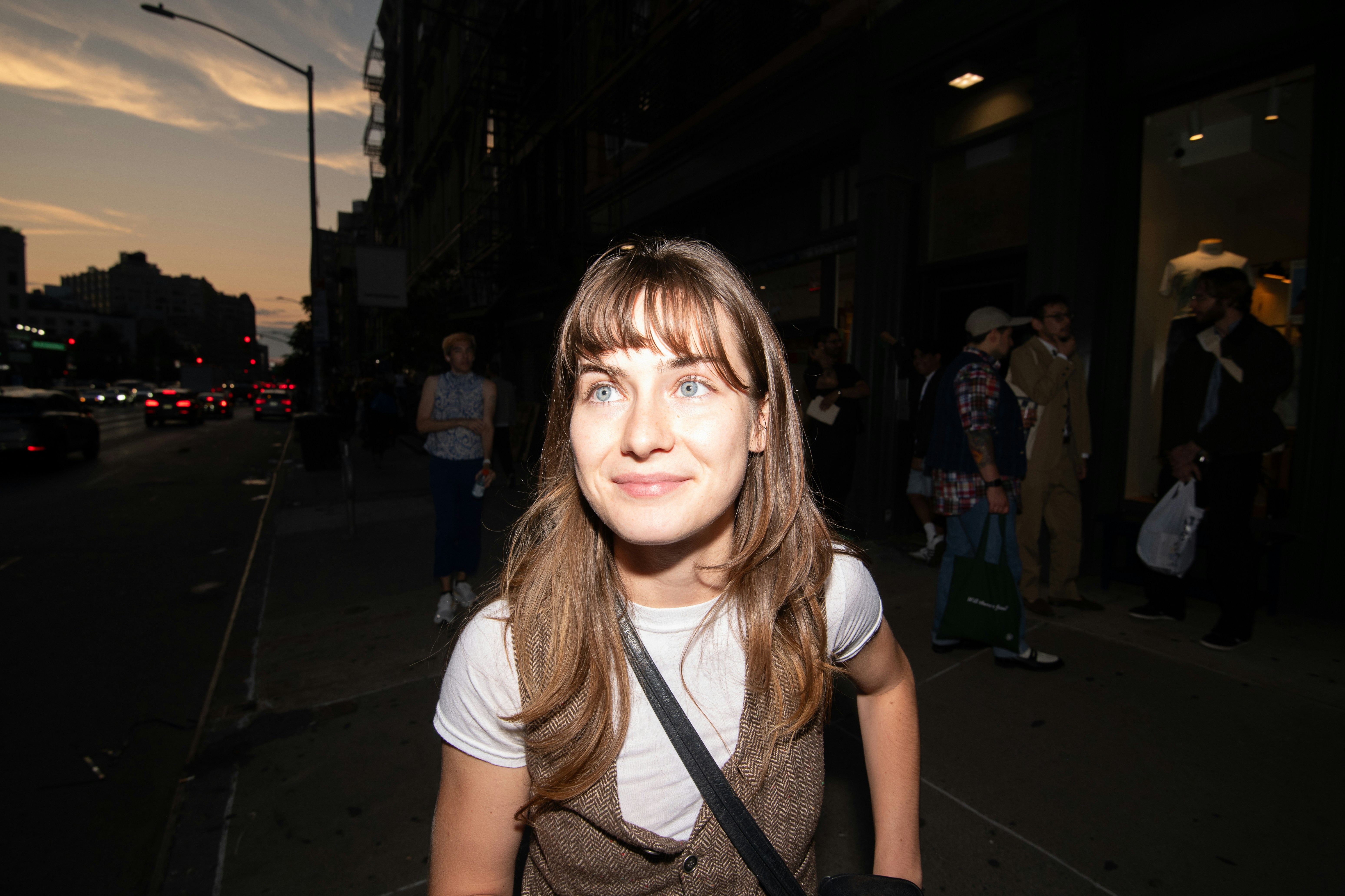 Woman standing on a city street at dusk.