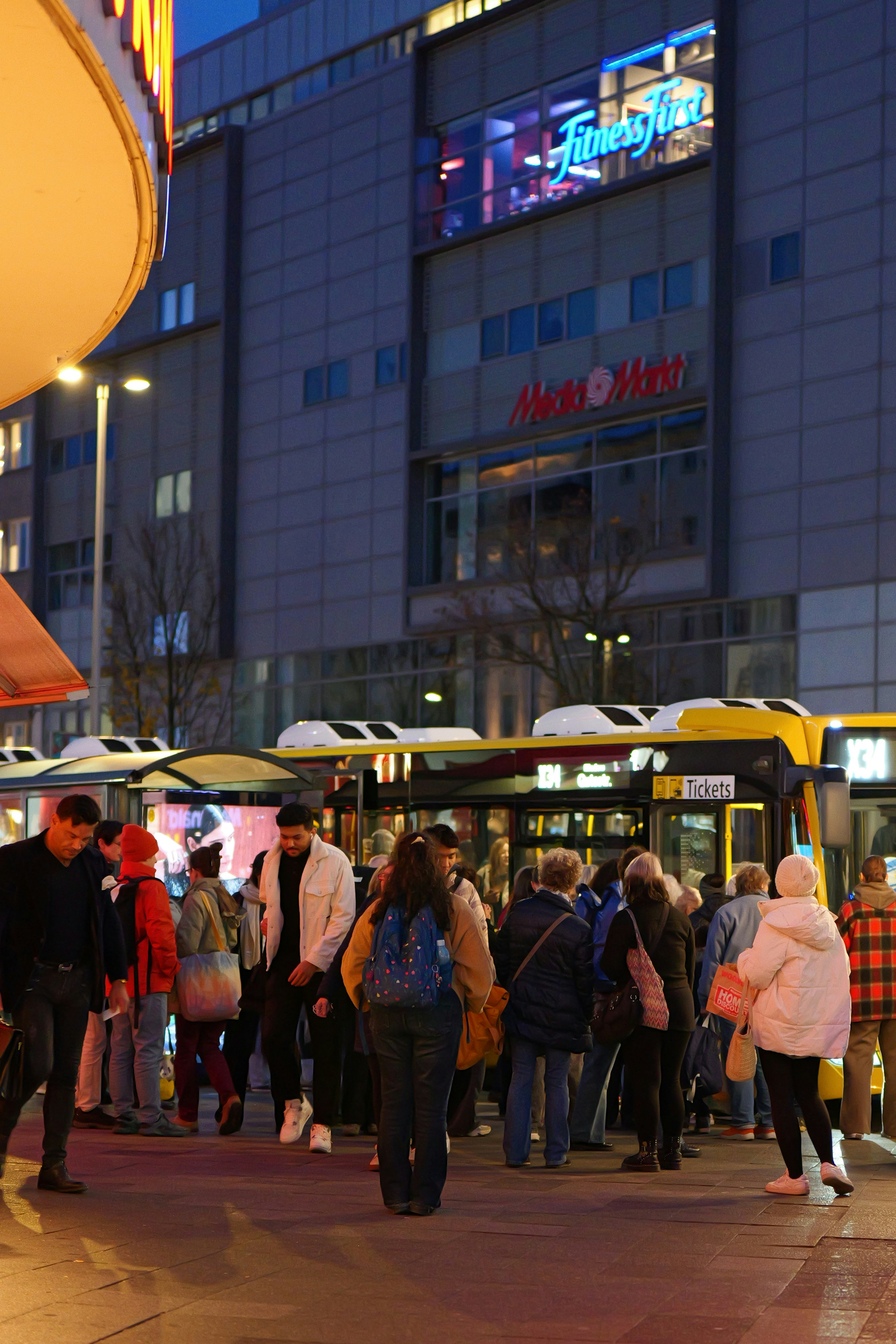 People waiting for bus outside modern building at dusk - people-waiting-for-bus-outside-modern-building-at-dusk-bIjzpCU6vWo