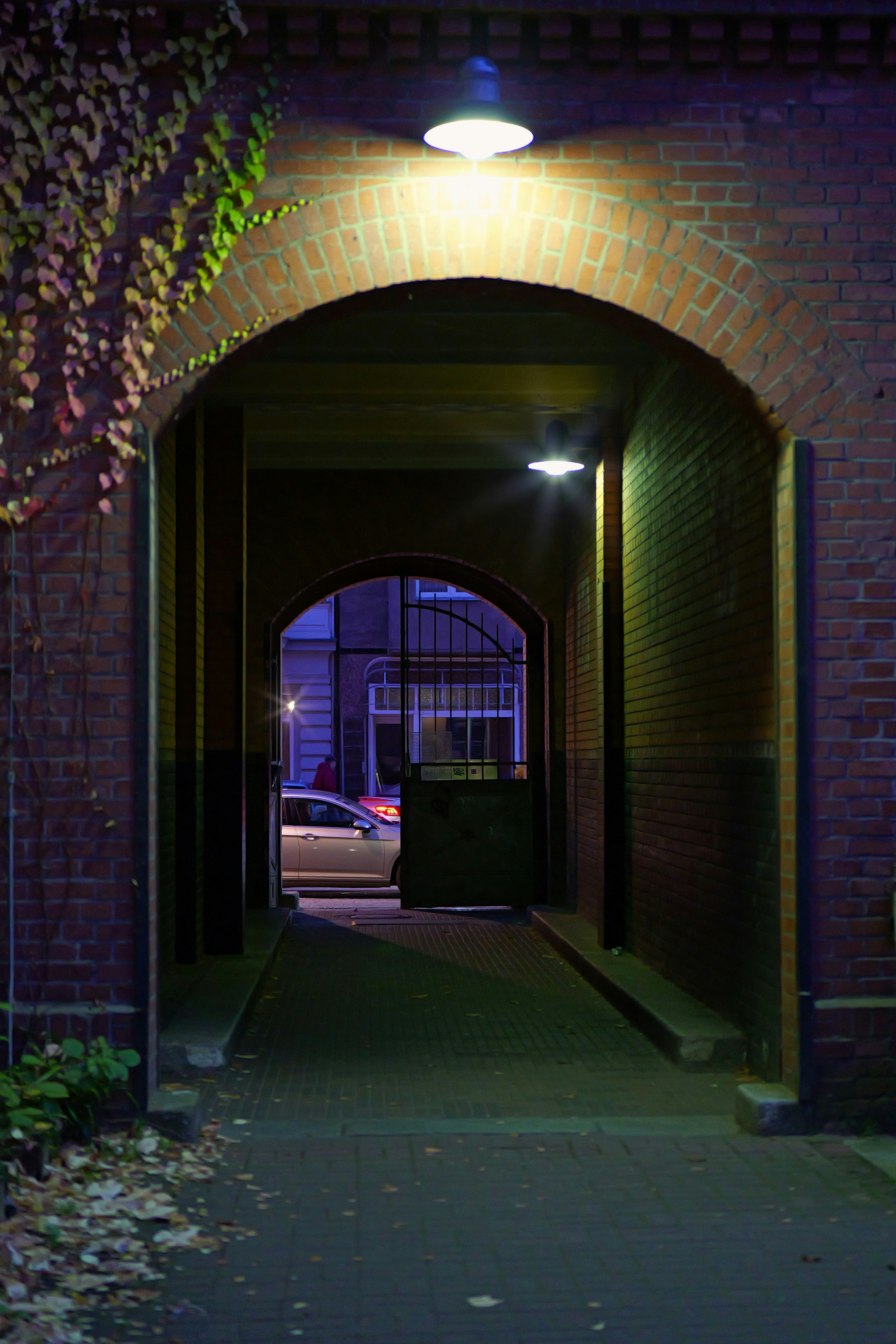 Brick archway leading to a dimly lit street at night. - brick-archway-leading-to-a-dimly-lit-street-at-night-pGmdf-o5mcg