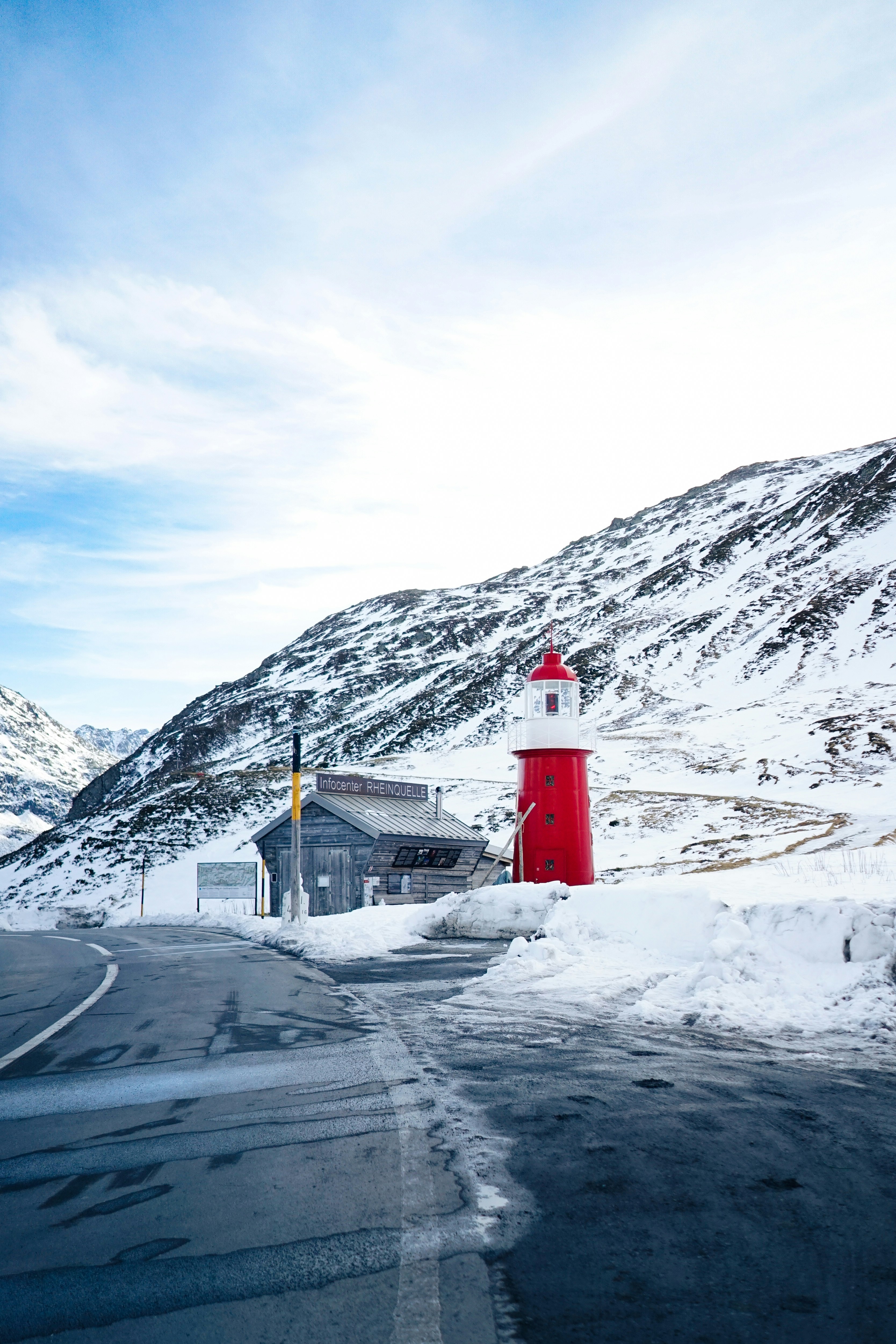 Red lighthouse structure beside snowy mountain road