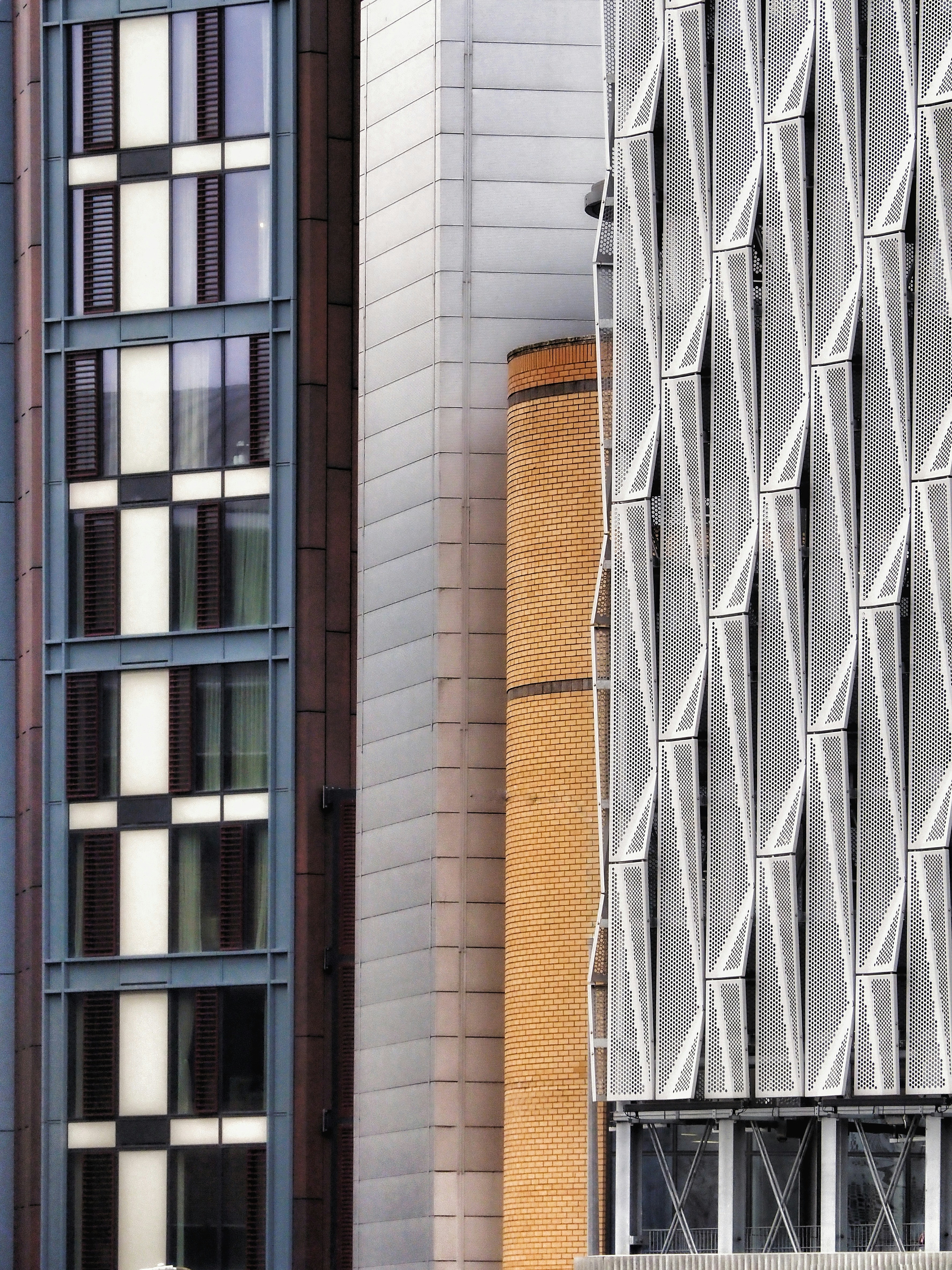 A sleek, modern office building in a UK business park with a facade of smooth, large-format composite panels in a charcoal grey color.