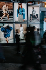 People walk past gucci advertisements at night.
