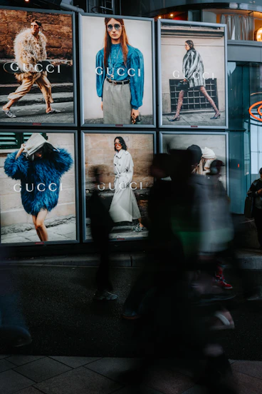 People walk past gucci advertisements at night
